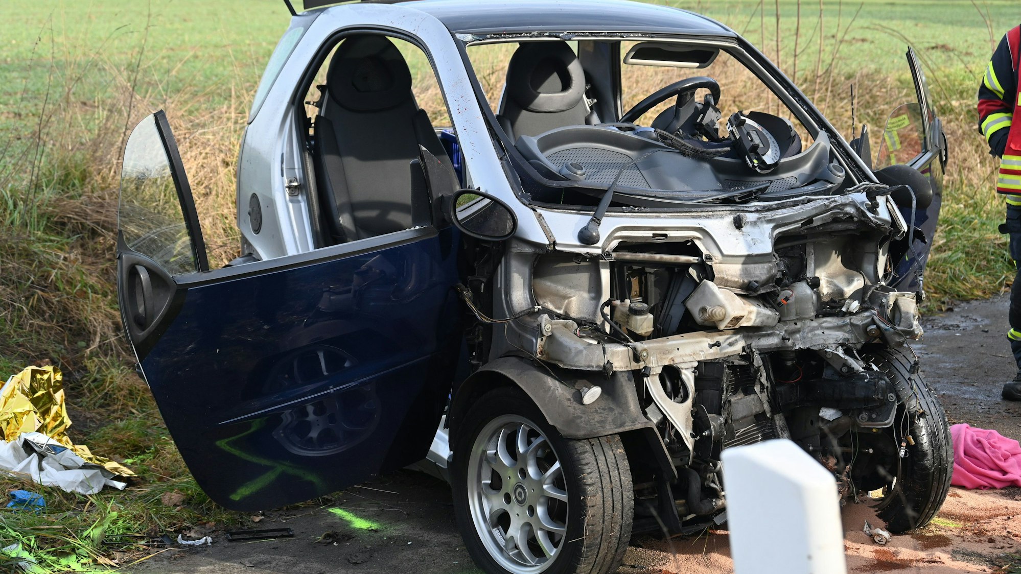 Das Bild zeigt einen verunfallten Kleinwagen am Straßenrand.