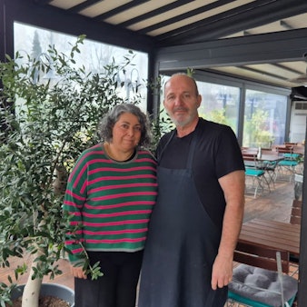 Eine Frau und ein Mann stehen im Wintergarten eines Restaurants.