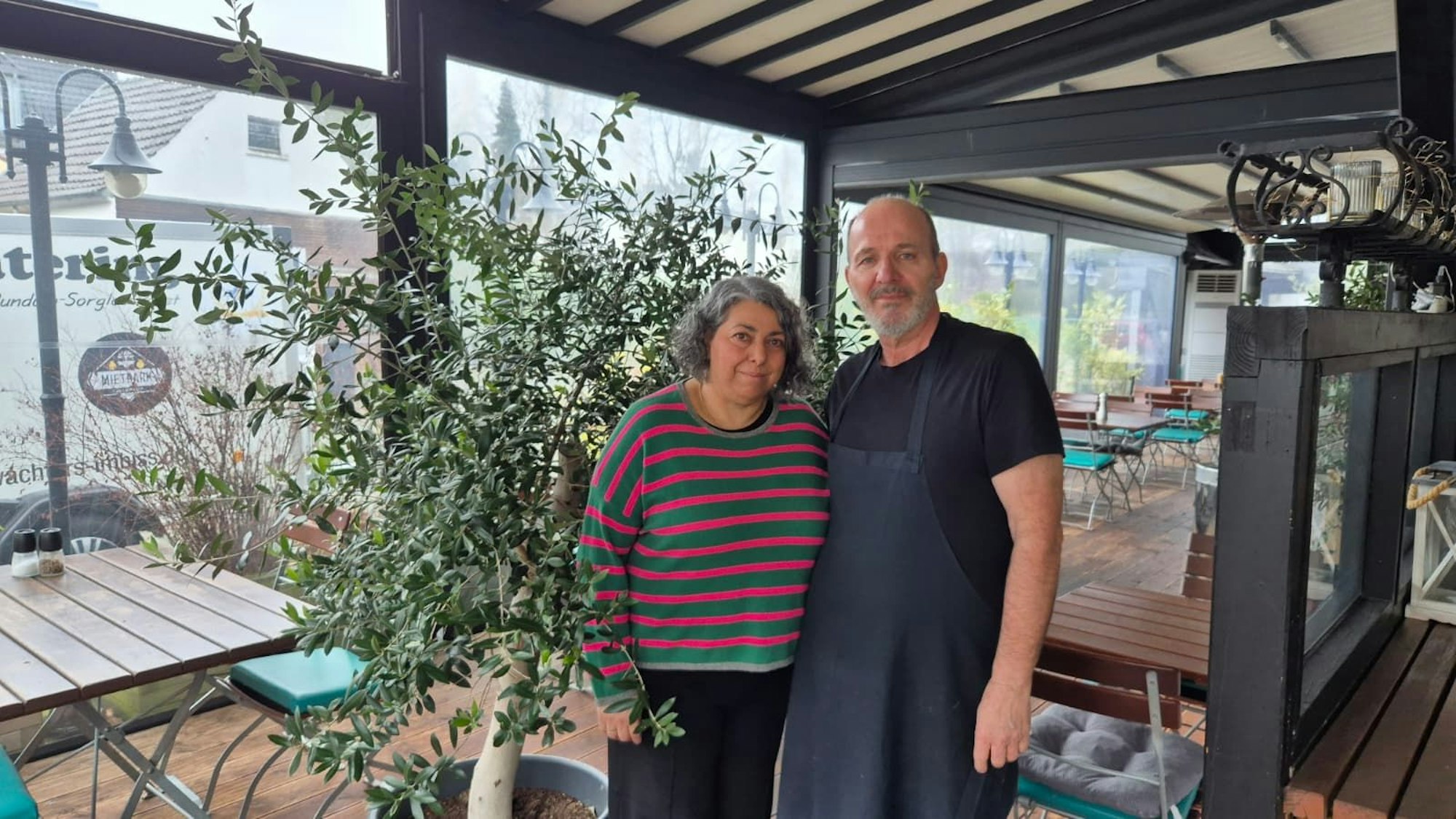 Eine Frau und ein Mann stehen im Wintergarten eines Restaurants.