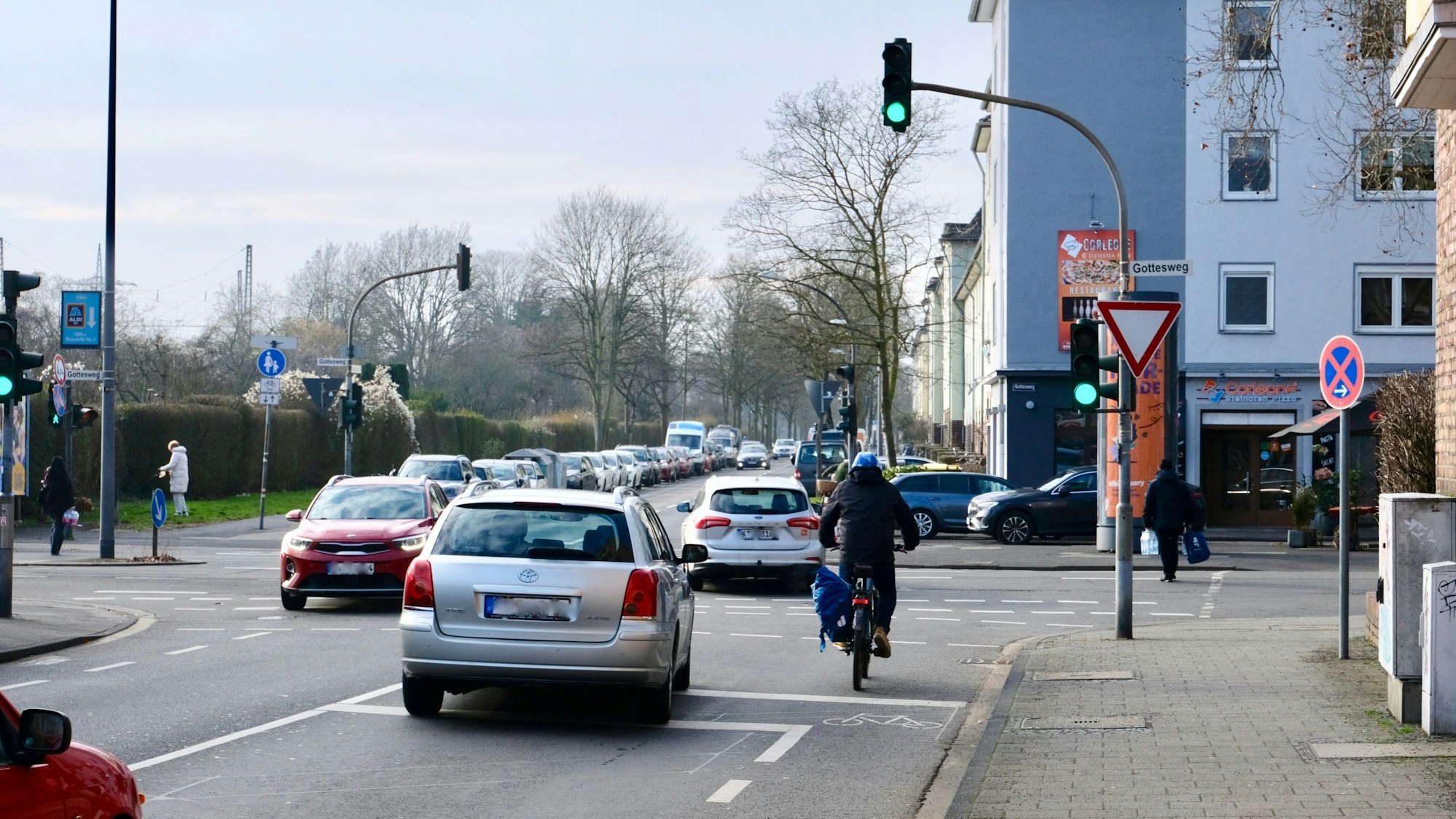 An einer Kreuzung mit Ampel fahren Radfahrer und Autos bei Grün an.