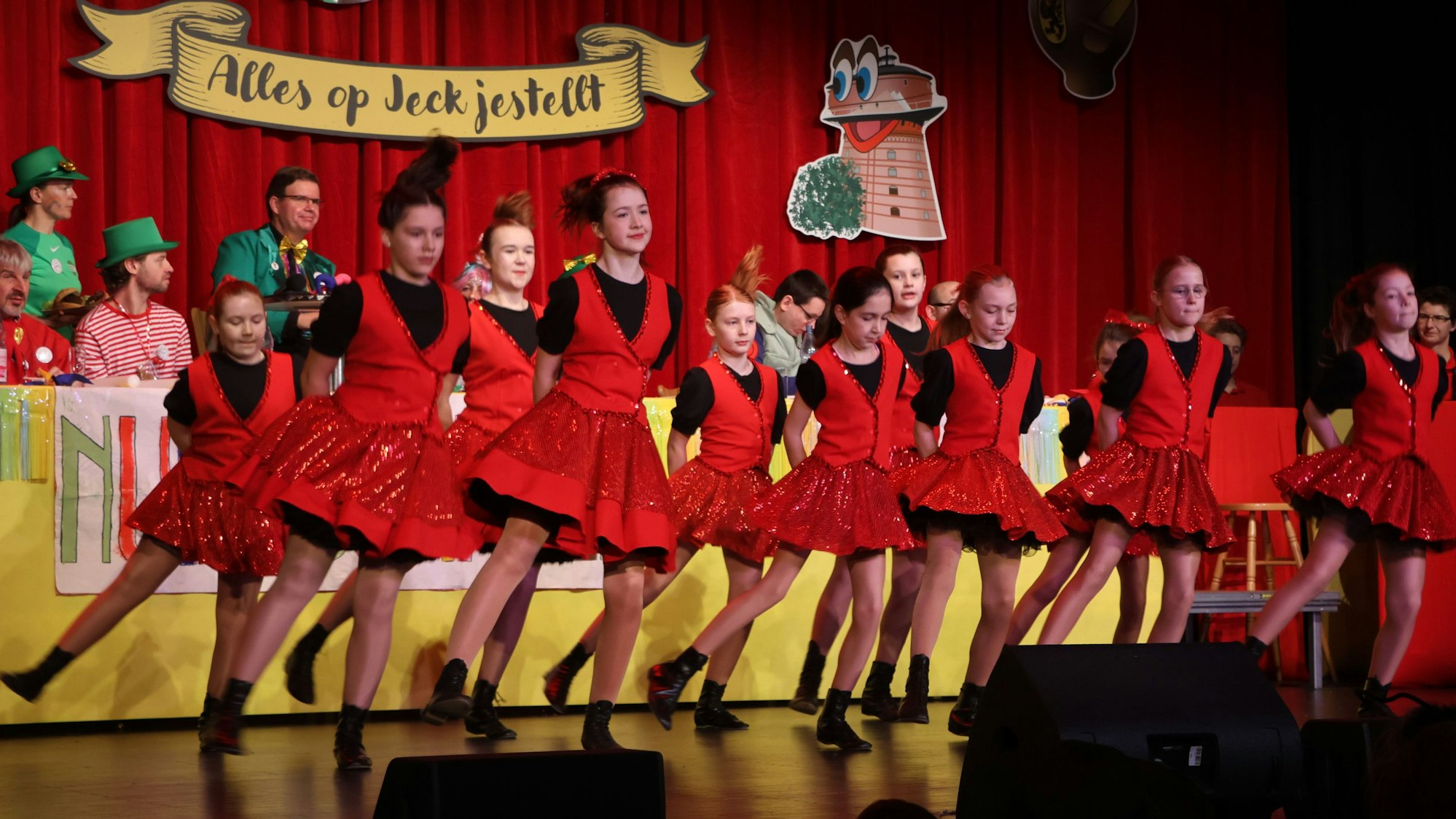 Auf dem Bild sind tanzende Mädchen in roten Kostümen zu sehen.