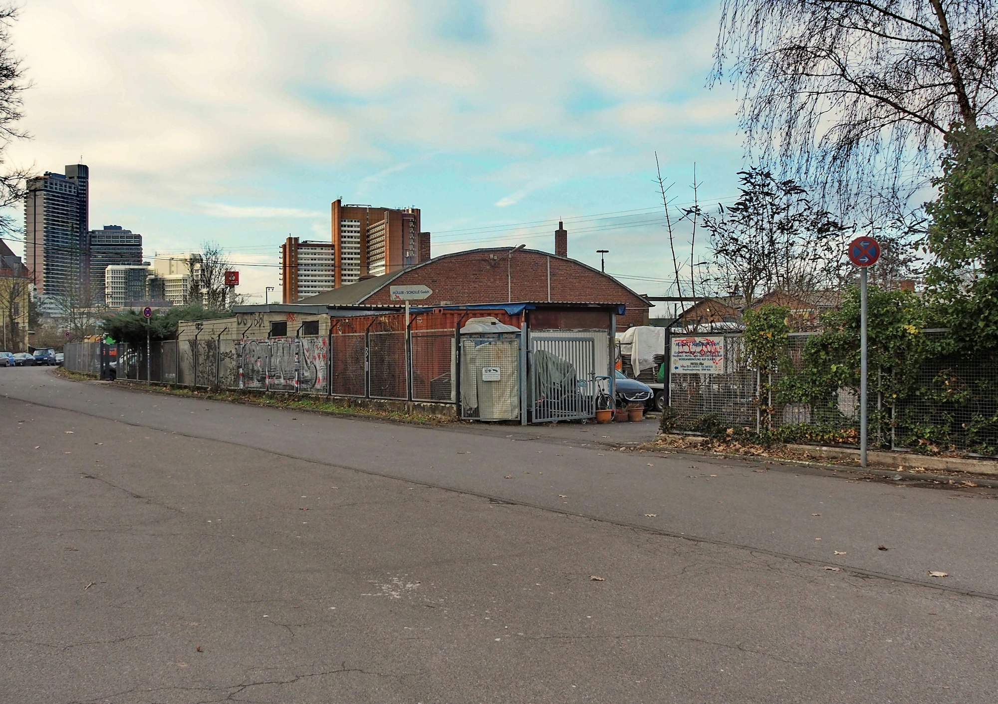 Vereinzelte Gebäude stehen auf einem Firmengelände an einer Straße.