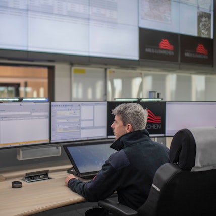 Ein Mann sitzt vor einer Reihe von Bildschirmen.