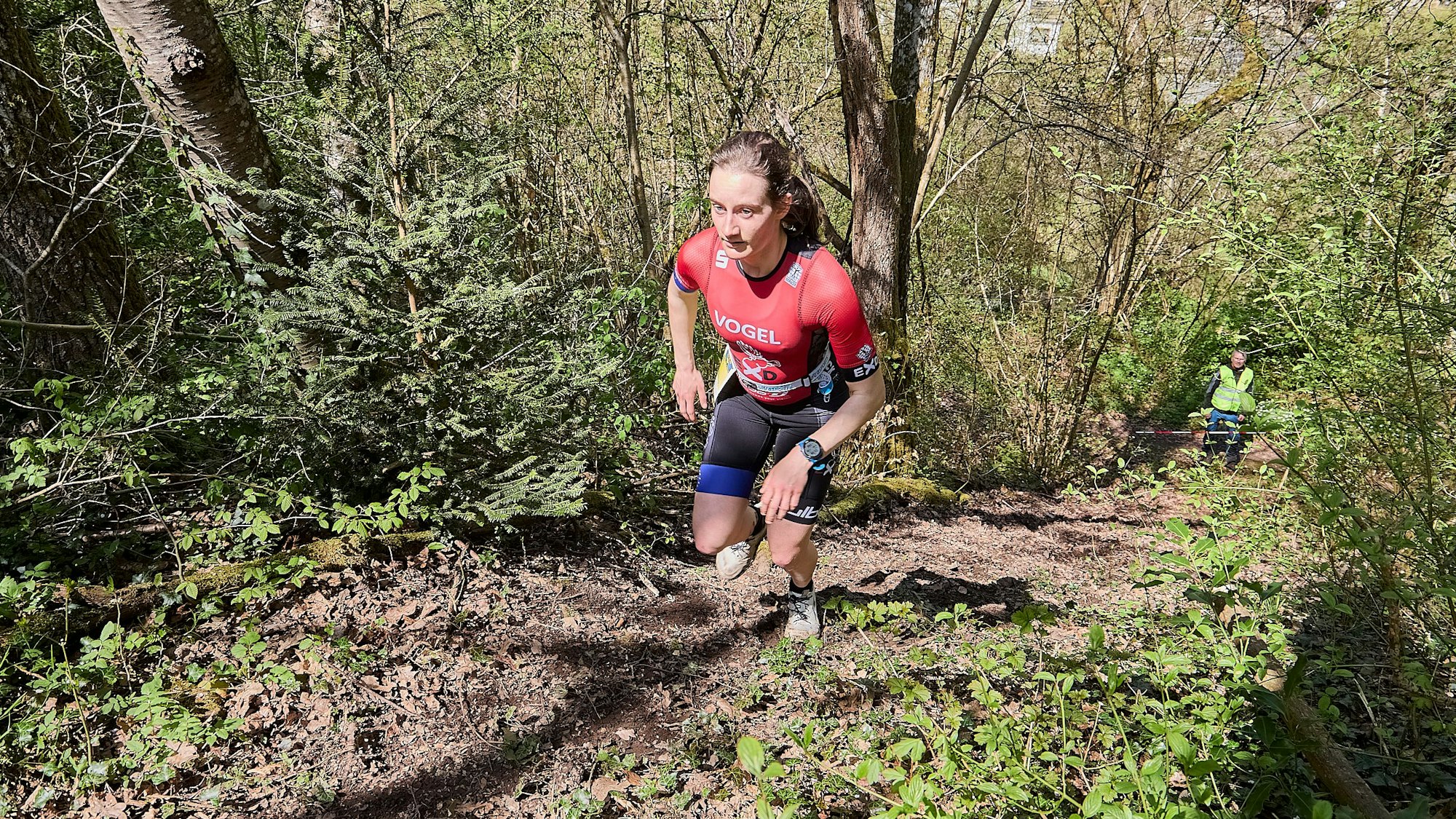 Milena Voge läuft in Sportkleidung ein treppiges Gelände in einem Waldstück hoch.