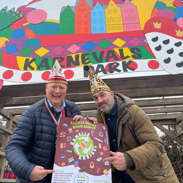 Das Foto zeigt den Landwirt und den Karnvalisten mit Karnevalsmützen und Plakat vor dem Karnevalspark auf dem Gertrudenhof.