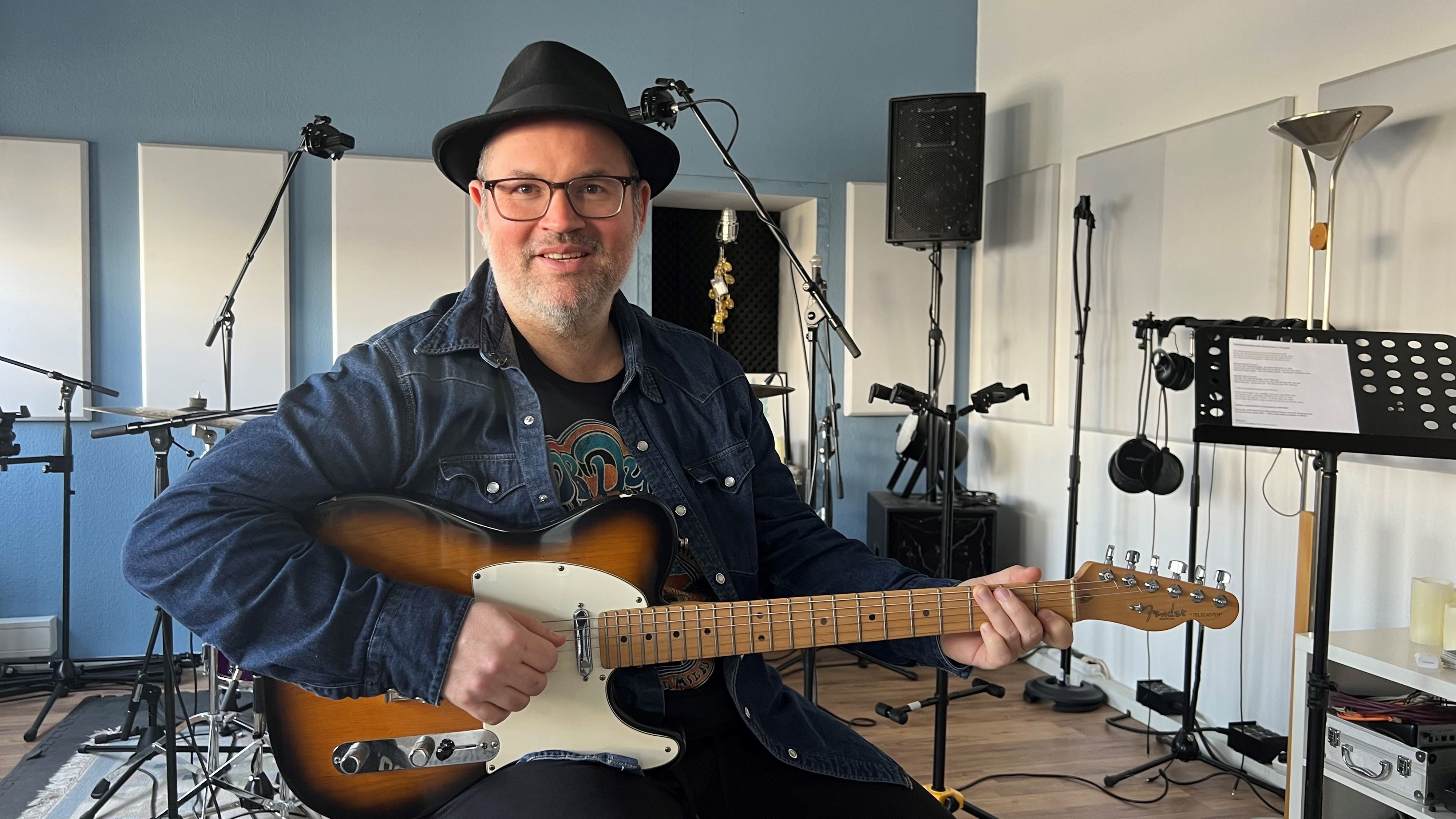 Björn Heuser sitzt mit Gitarre im Studio.