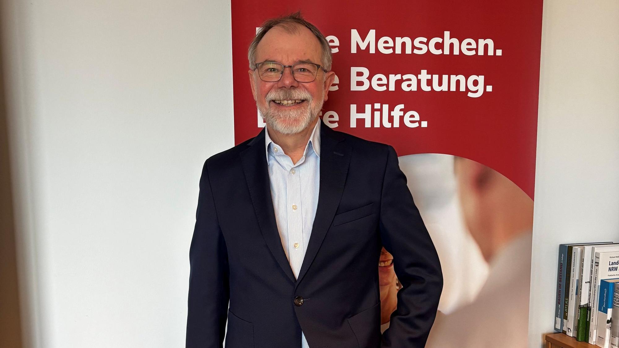 Wieler steht vor einem Banner der Verbraucherzentrale und lächelt in die Kamera.