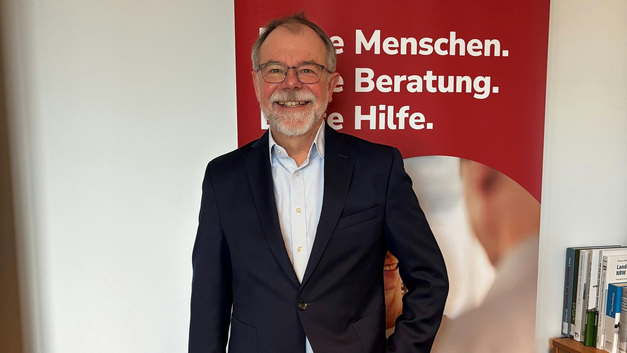 Wieler steht vor einem Banner der Verbraucherzentrale und lächelt in die Kamera.