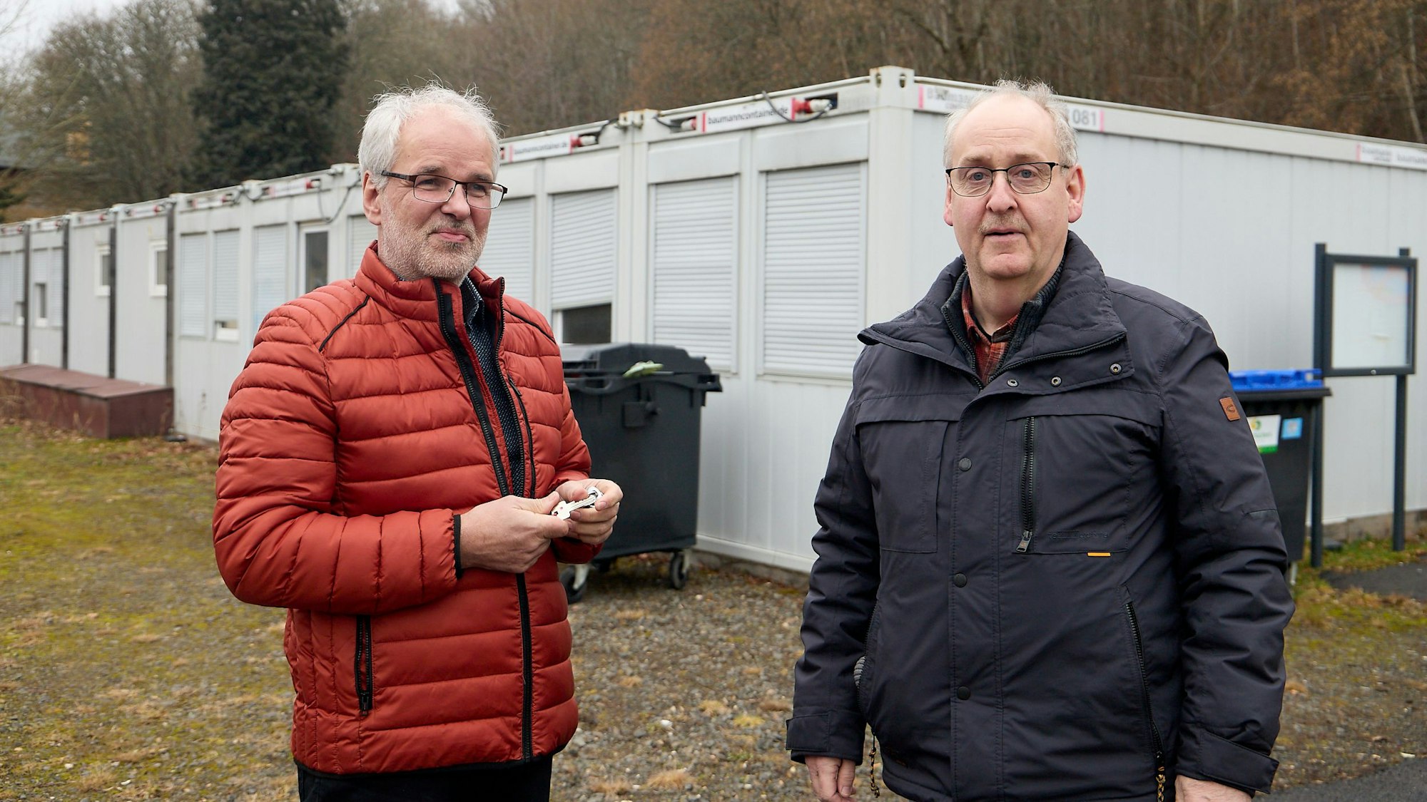 Das Bild zeigt die Obengenannten. Im Hintergrund sind Wohncontainer zu sehen.