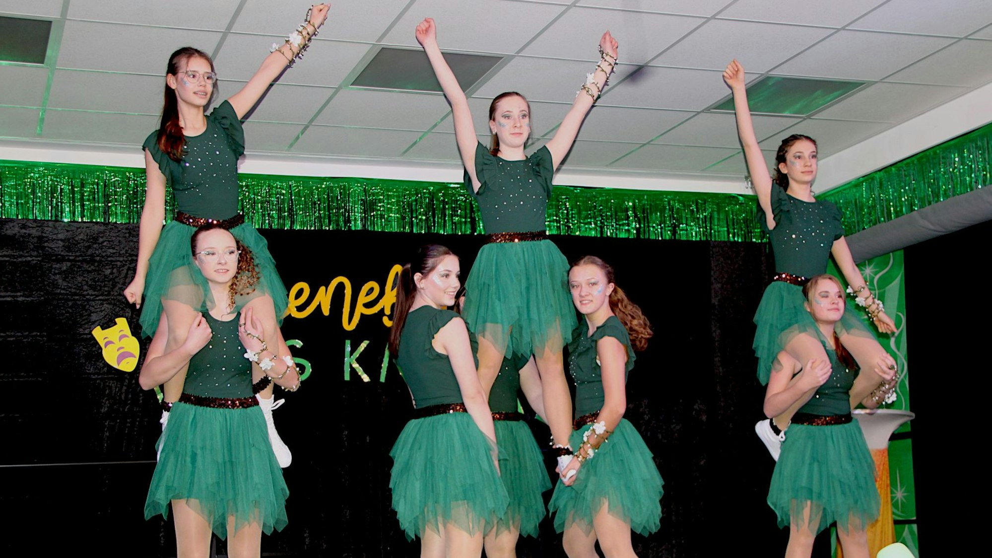 Eine Gruppe junger Tänzerinnen präsentiert Hebefiguren auf einer Bühen.