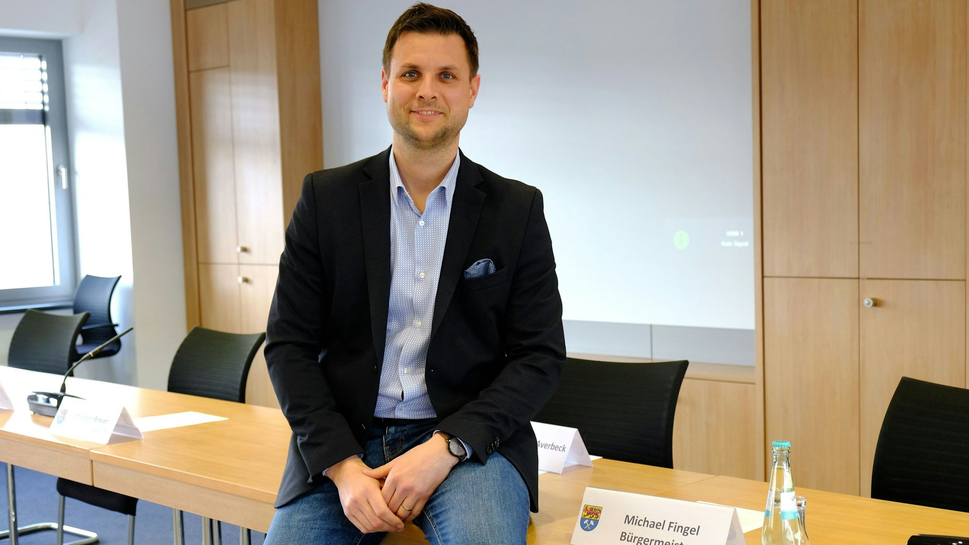 Bürgermeister Michael Fingel sitzt im Ratssaal lässig auf der Tischkante.