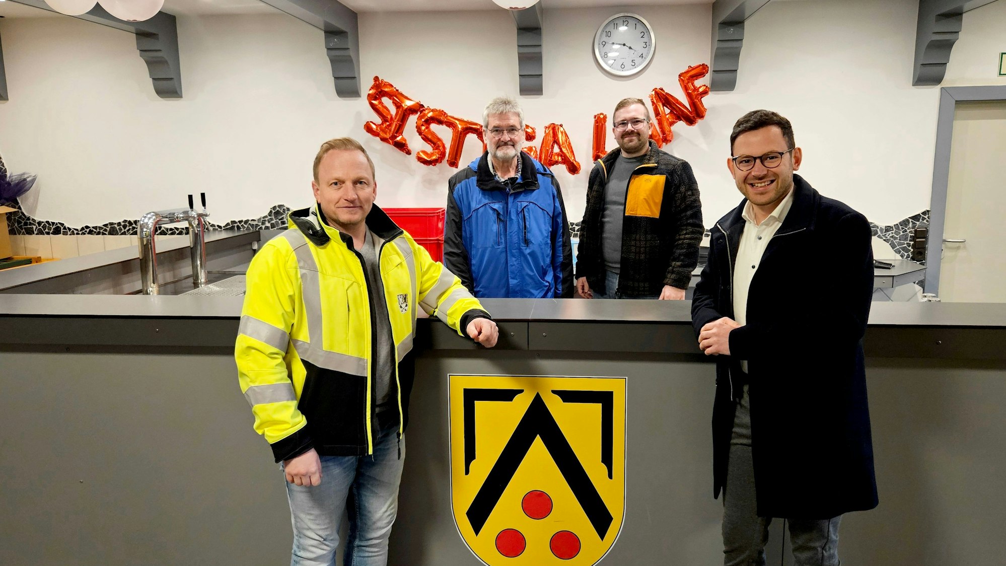 An der neuen Theke im Bürgerhaus in Kall-Sistig stehen vier Männer.