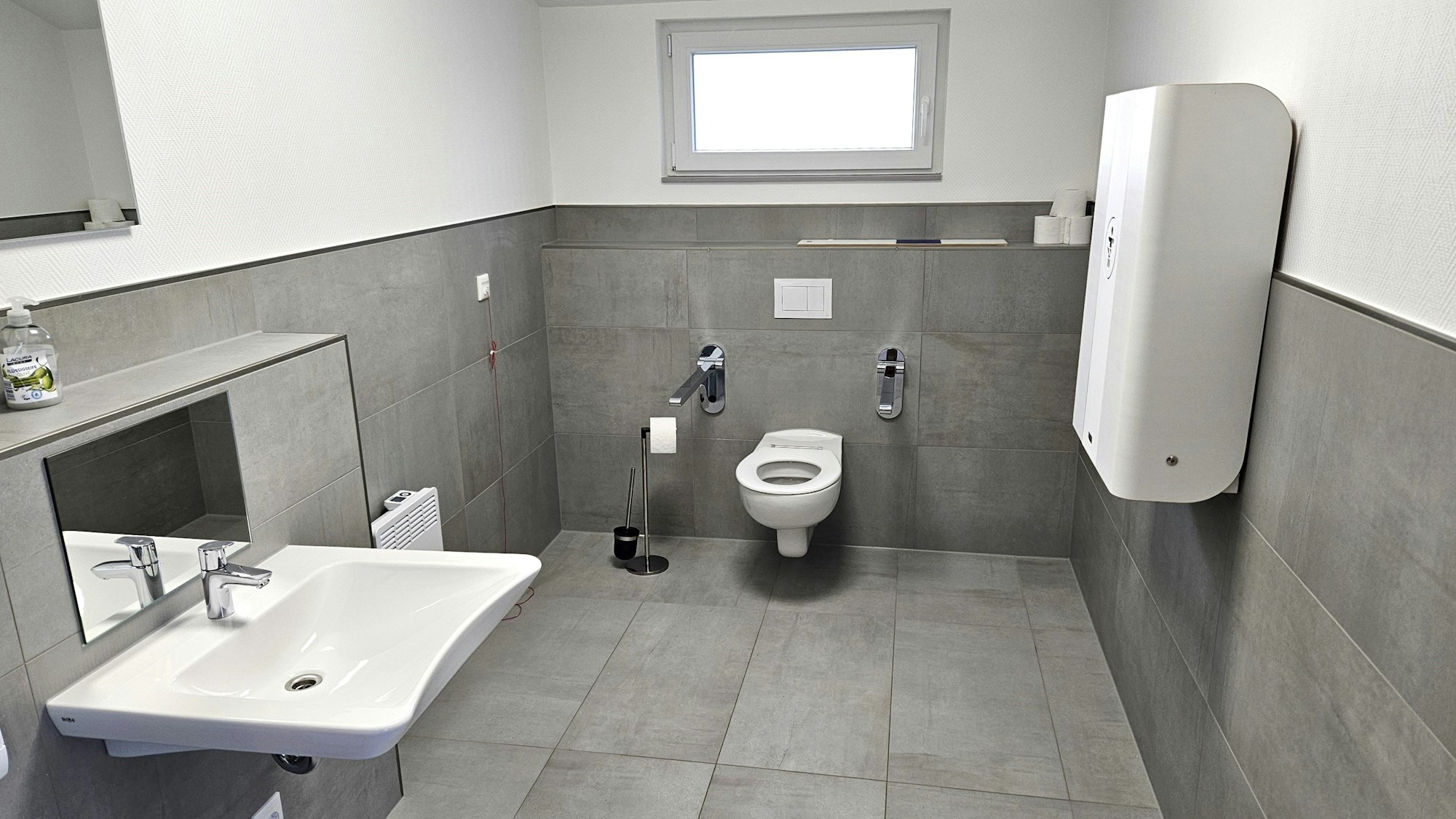 Blick in die Sanitäranlage für Menschen mit Behinderung. Rechts an der Wand hängt ein Wickeltisch.