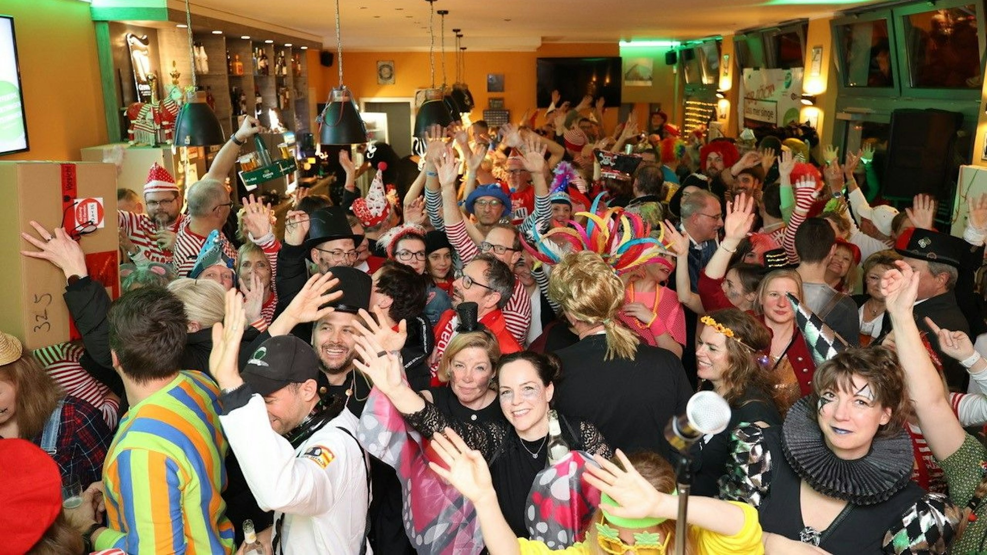 Karnevalistisch gekleidetes Publikum feiert in einer Bar.