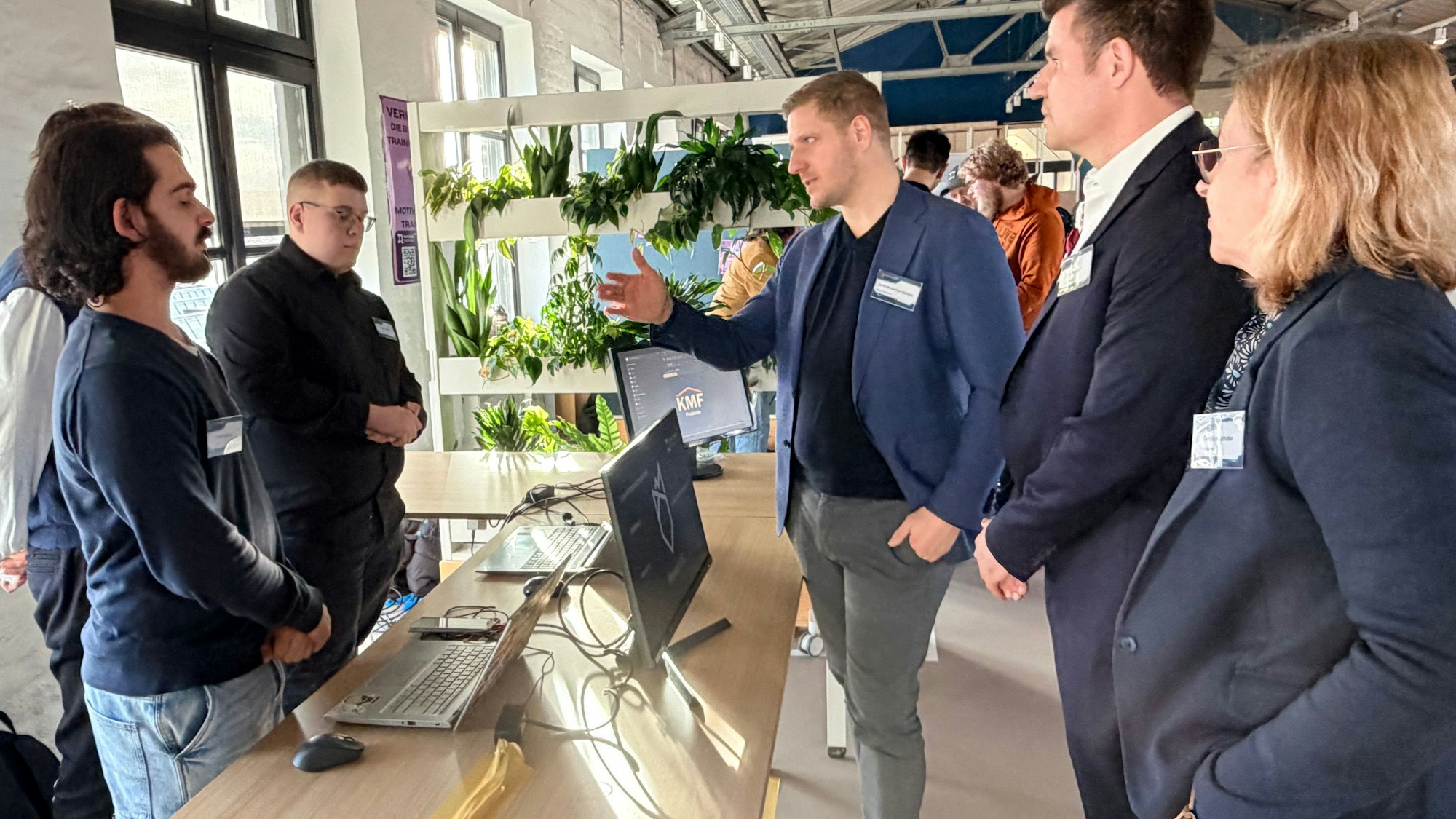 Drei Schüler stehen an ihrem Stand, auf dem Tisch vor sich Computer. Sie sind im Gespräch mit Landrat Markus Ramers,TEB-Bereichsleiter David Breuer und Schulleiterin Carolin Holzhüter.