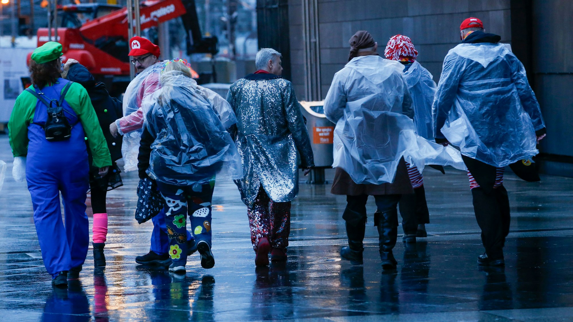Zu früher Stunde und im Nieselregen machen sich diese Jecken am Kölner Hauptbahnhof auf den Weg.