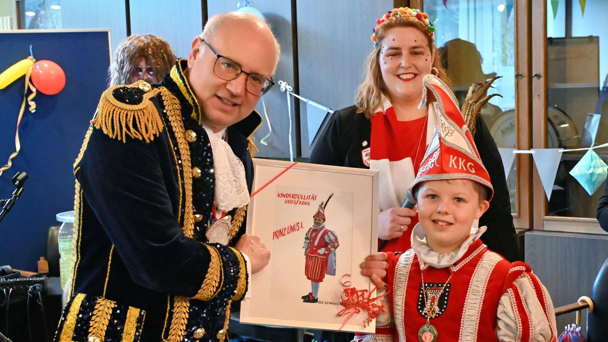 Heimbachs Bürgermeister Jochen Weiler ist kostümiert und zeigt Kinderprinz Linus sein Bild für die Tollitätengalerie.
