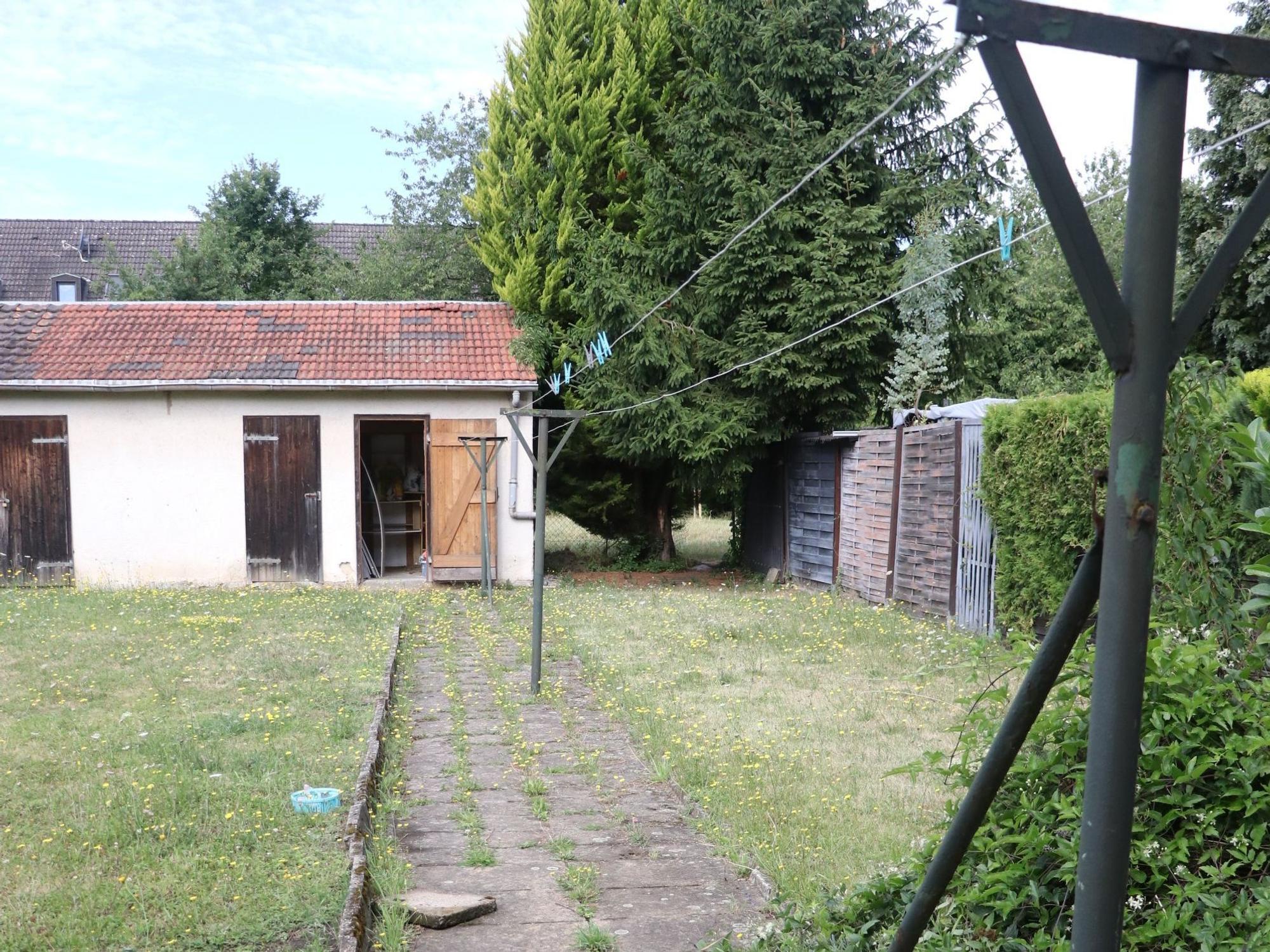 Auf dem Bild ist ein alter Schuppen in einem Garten zu sehen.