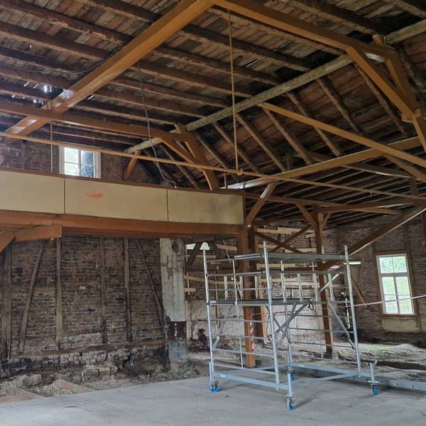 Zu sehen ist ein entkernter Saal, dessen Wände mit Fachwerk gebaut sind.