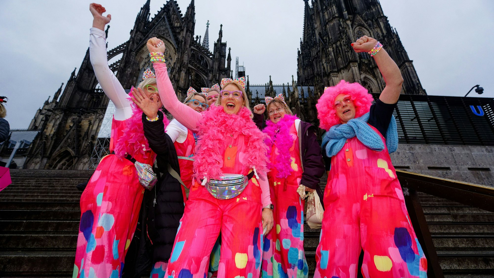 Karnevalistinnen feiern an Weiberfastnacht auf dem Weg in die Altstadt vor dem Dom.