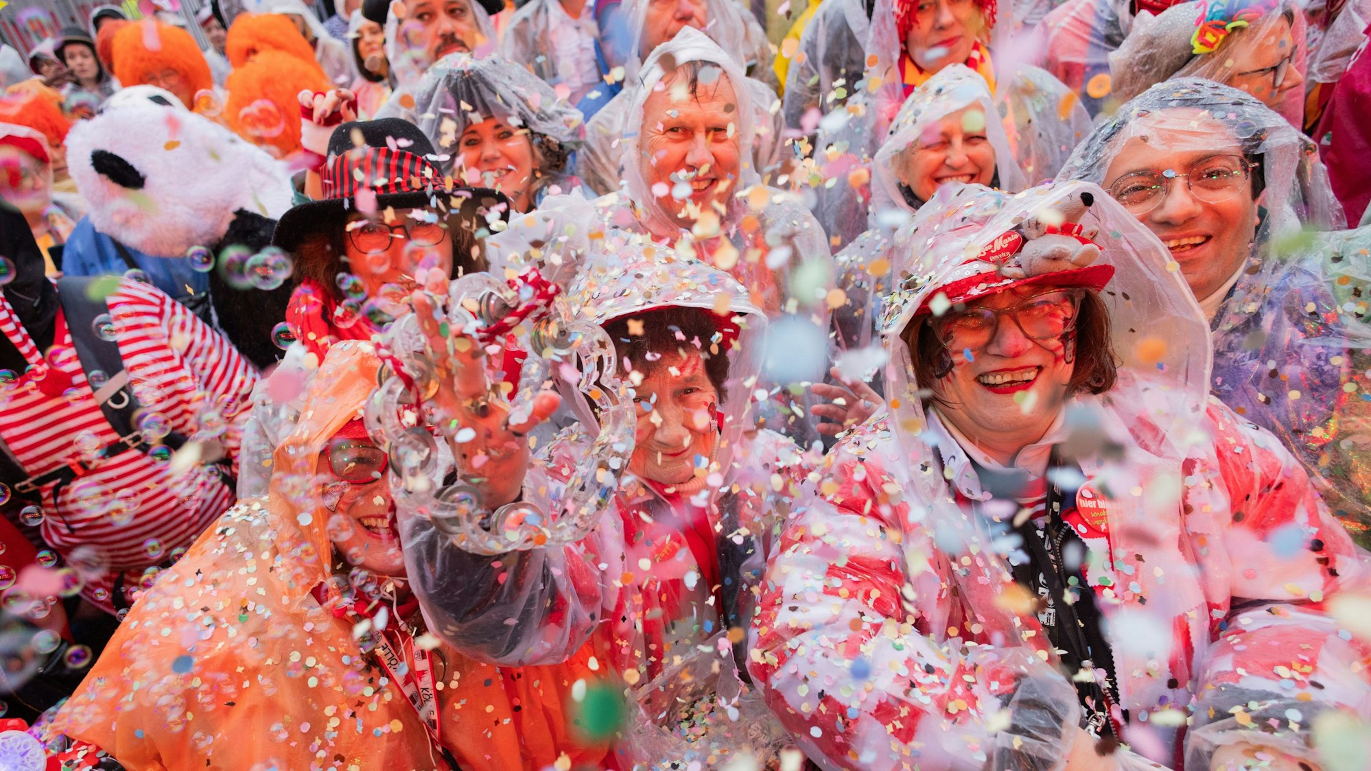 Die Jecken am Alter Markt lassen das Konfetti fliegen. Sie haben sich mit Capes auf den Regen eingestellt.