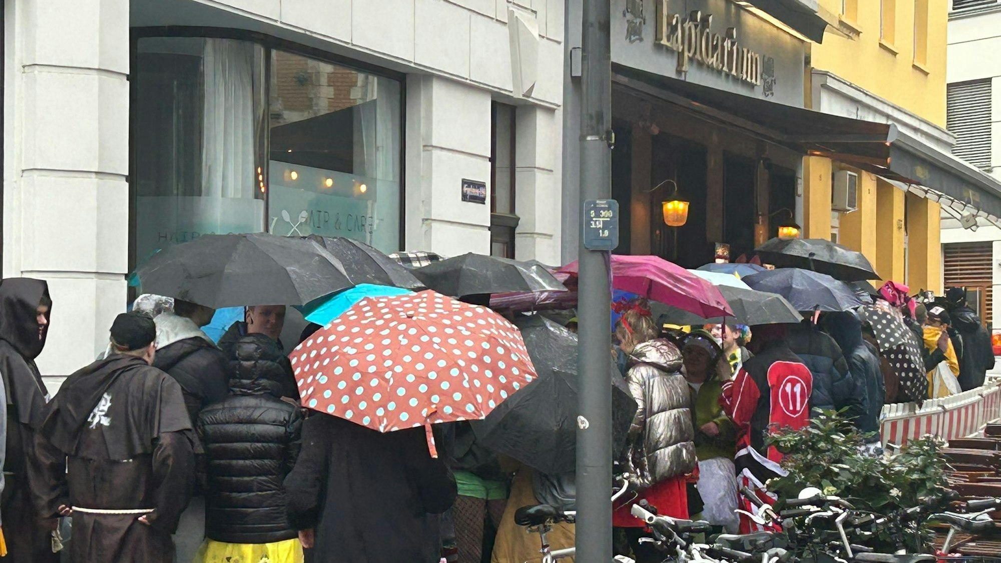 Im Regen in der Schlange stehen: ein häufiges Bild am Morgen von Weiberfastnacht in Köln.
