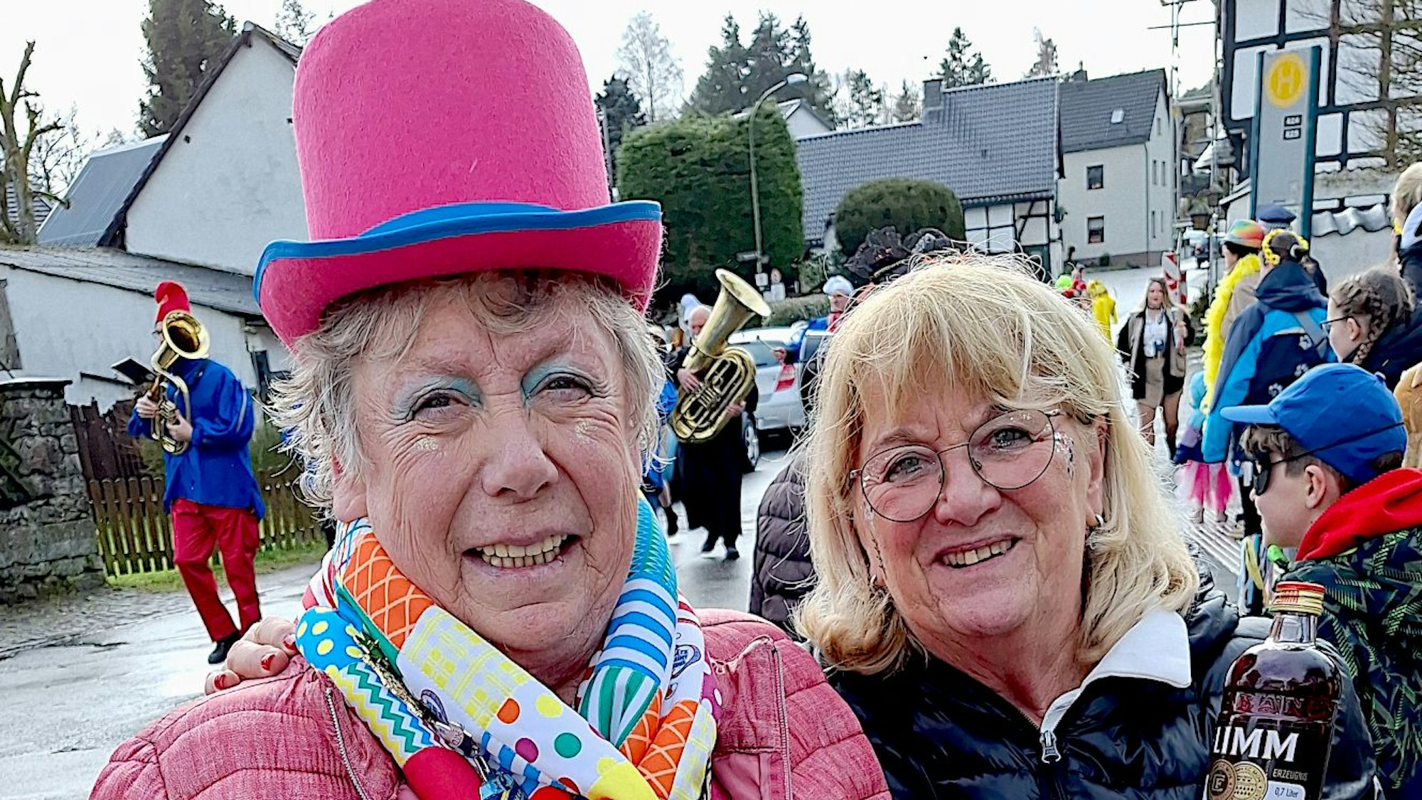 Eine Möhn mit einer großen rosa Melona auf dem Kopf steht neben einer Frau, die eine Flasche in der Hand hält.