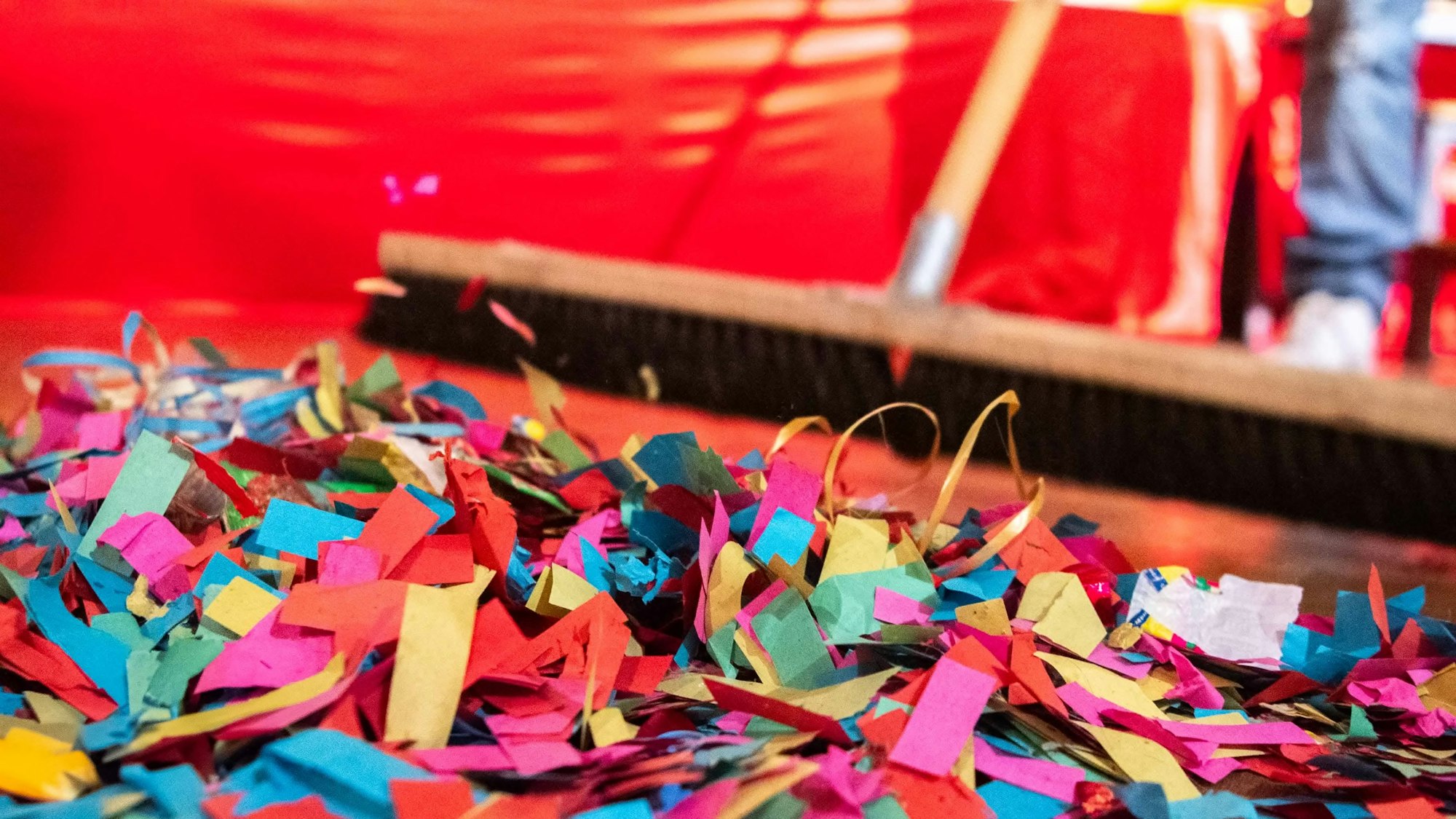 Das Foto zeigt, wie Konfetti mit einem Besen zusammengekehrt wird.