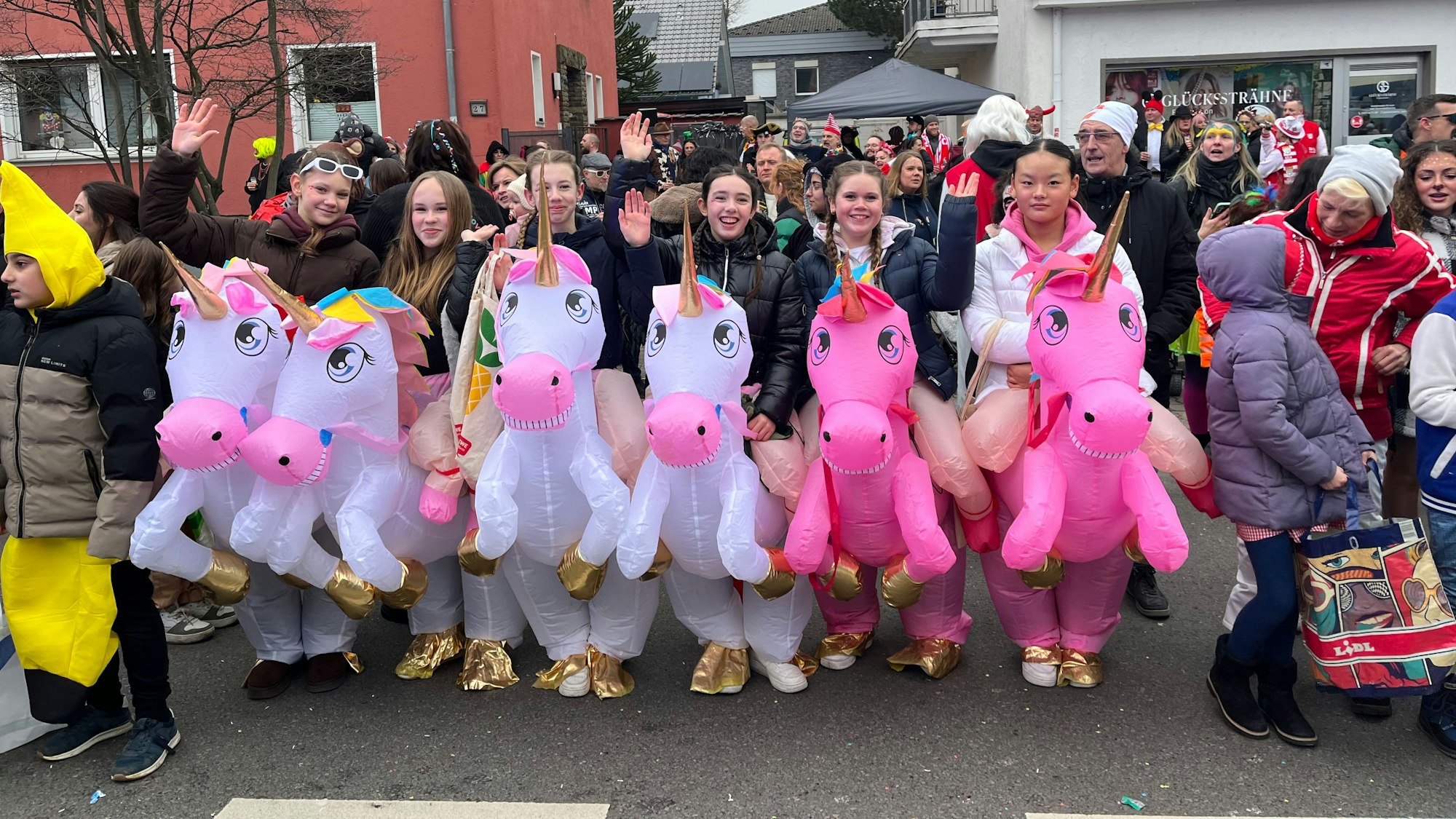 Am Zugweg sind sechs junge Mädchen mit aufgepumpten Einhörnern.
