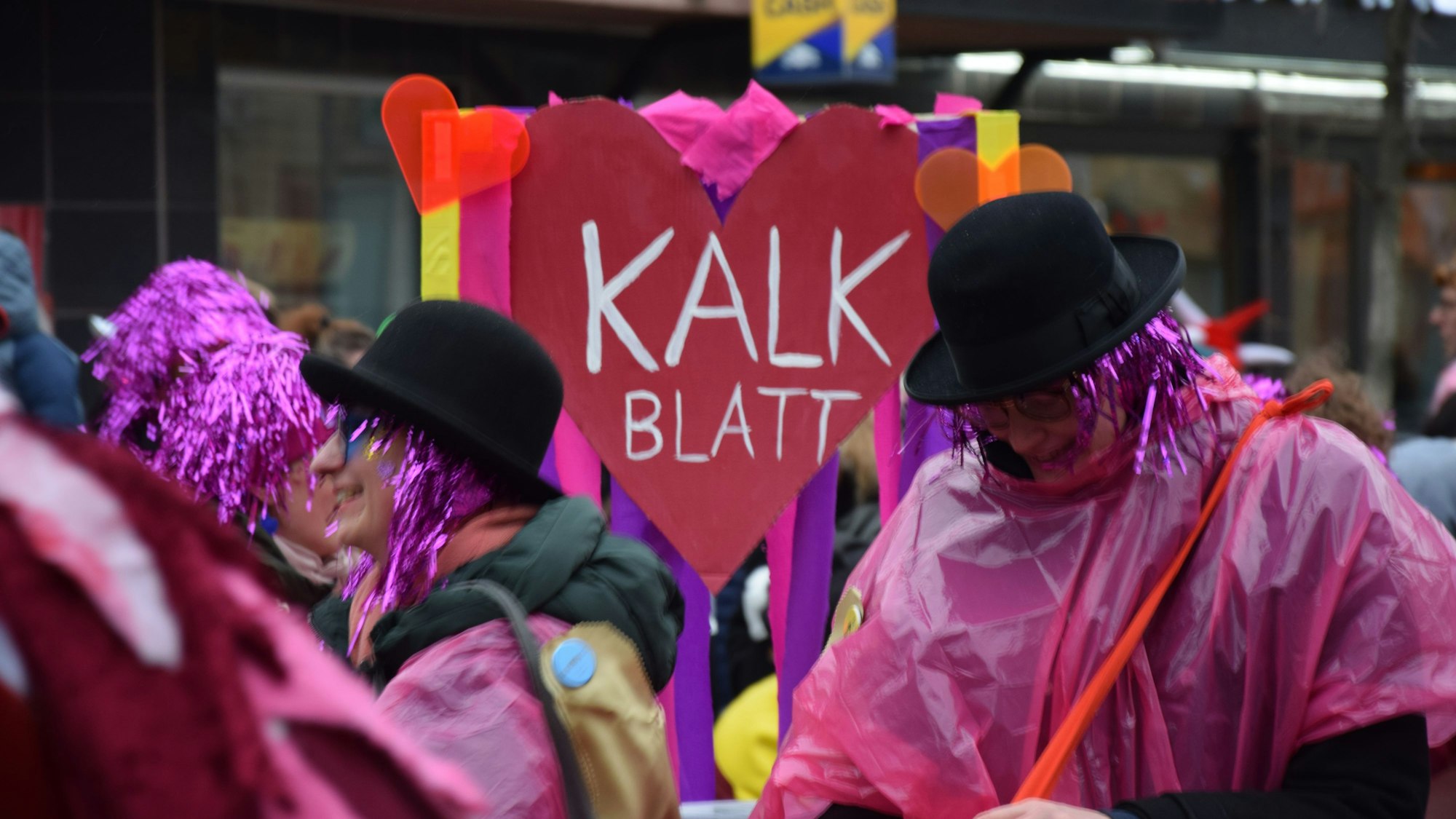 Menschen in lila Perücken und Melonen laufen durchs Veedel.