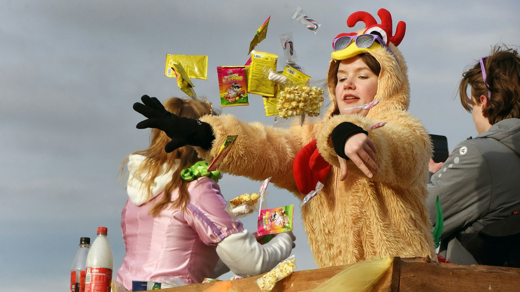 Eine Jecke schmeißt Kamelle von einem Karnevalswagen.