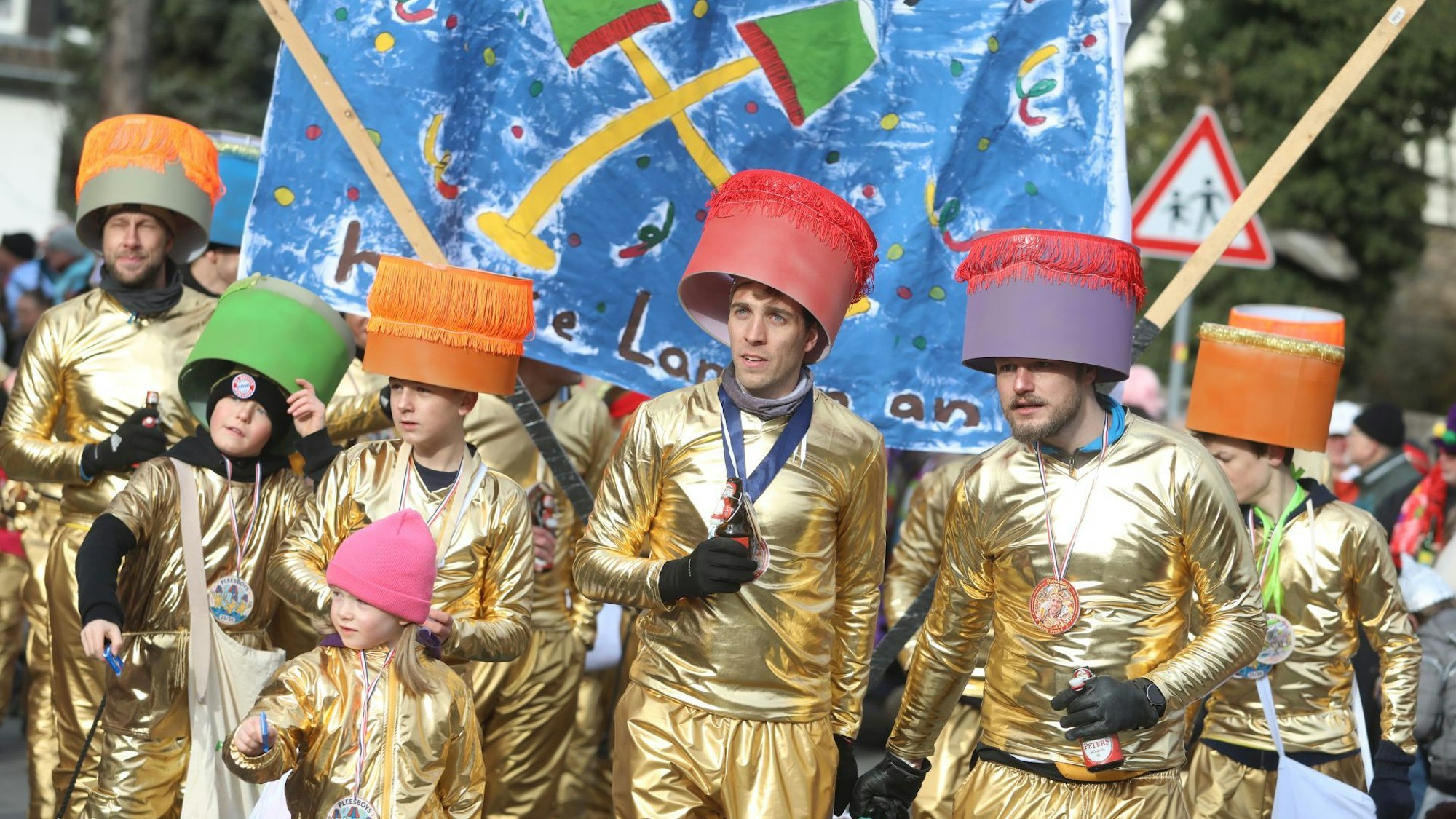 Eine Gruppe in goldenen Kostümen geht als Stehlampen durch die Straßen.