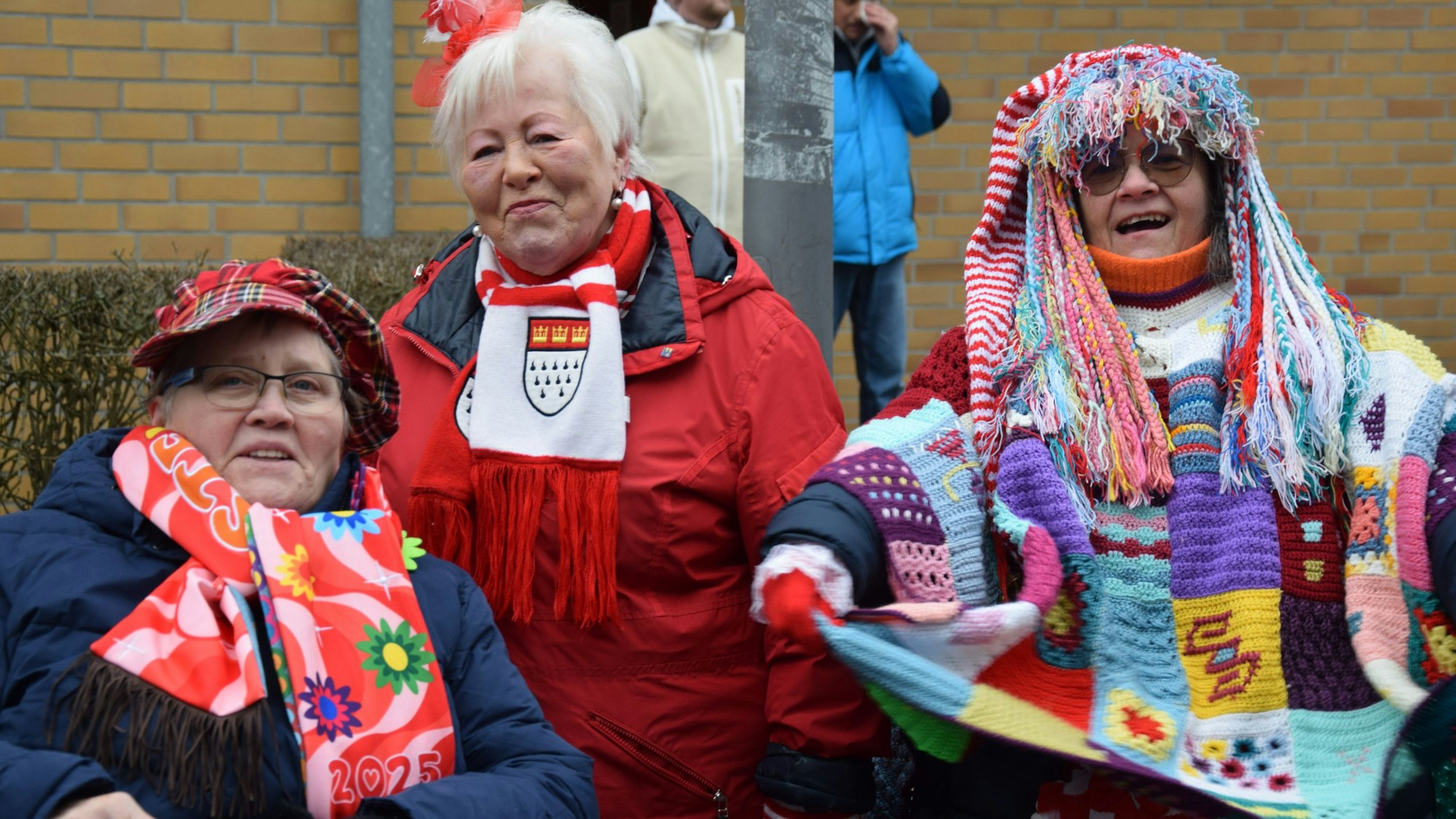 Drei ältere Damen mit teils selbst gestricktem Outfit stehen lachend am Zugweg.