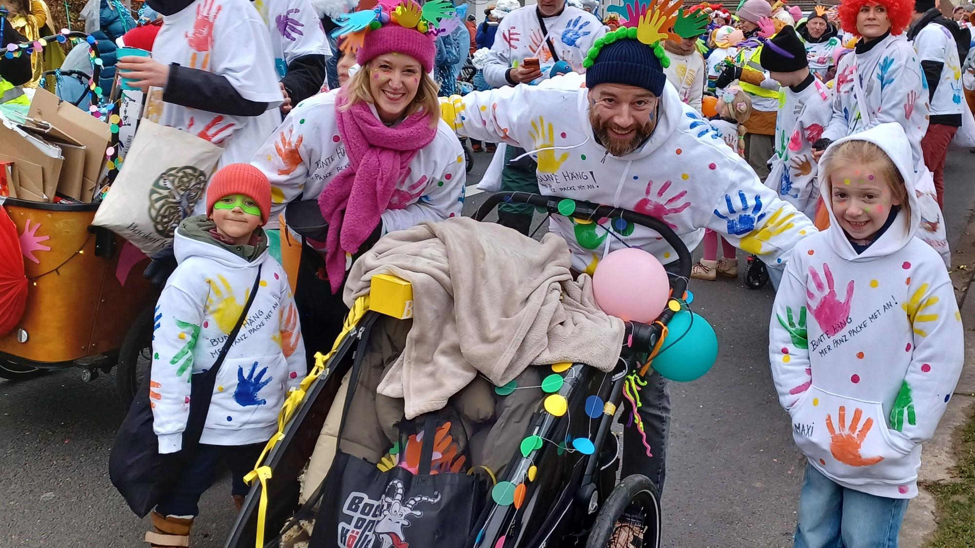 Kinder mit Hoodies, auf denen bunte Handabdrücke sind, laufen im Zoch mit.
