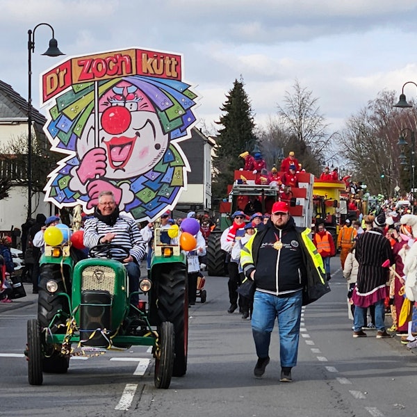 Auf einem Traktor ist ein Schild befestigt, das einen Clown zeigt.