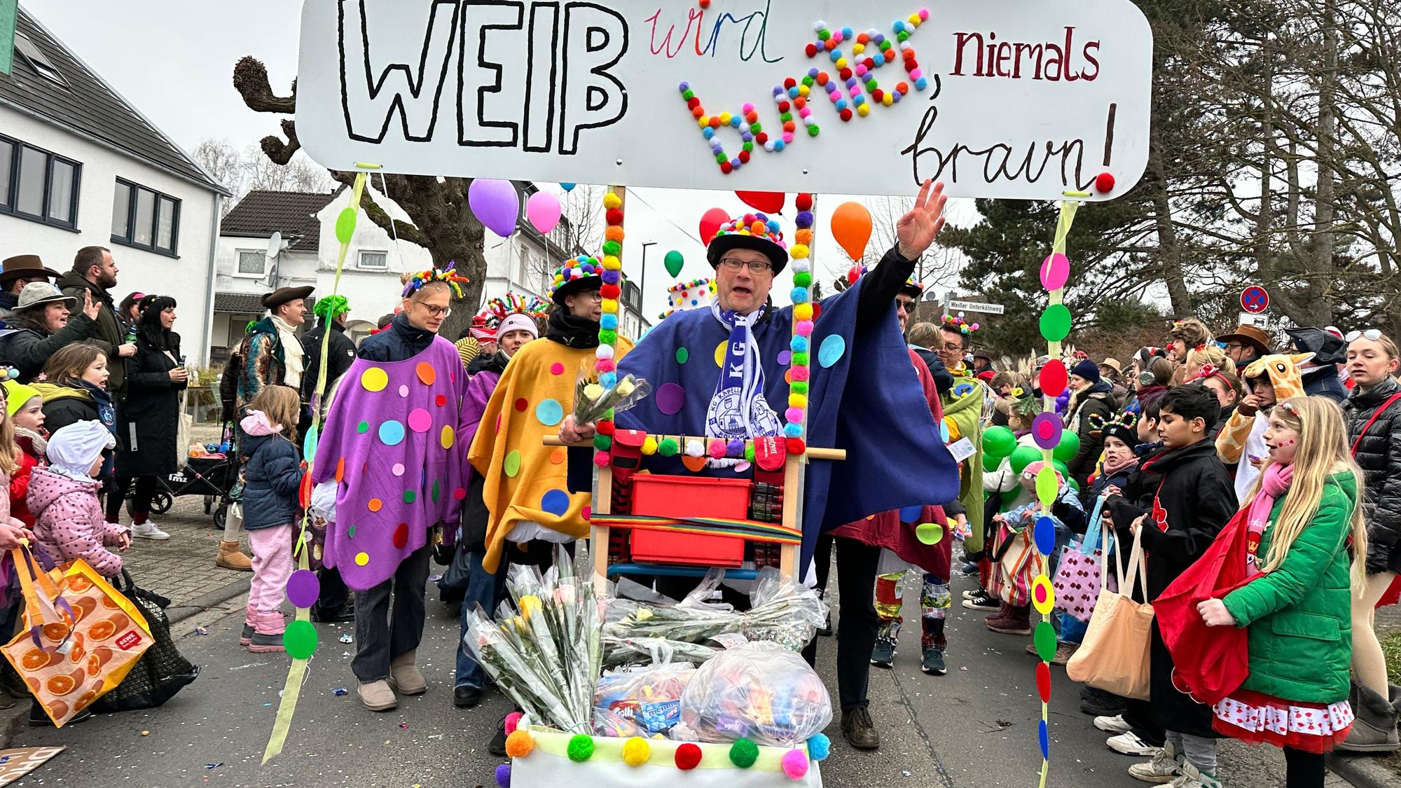 Eine Fußgruppe läuft mit einem Schild durch eine Straße: Weiß wird bunt, niemals braun.