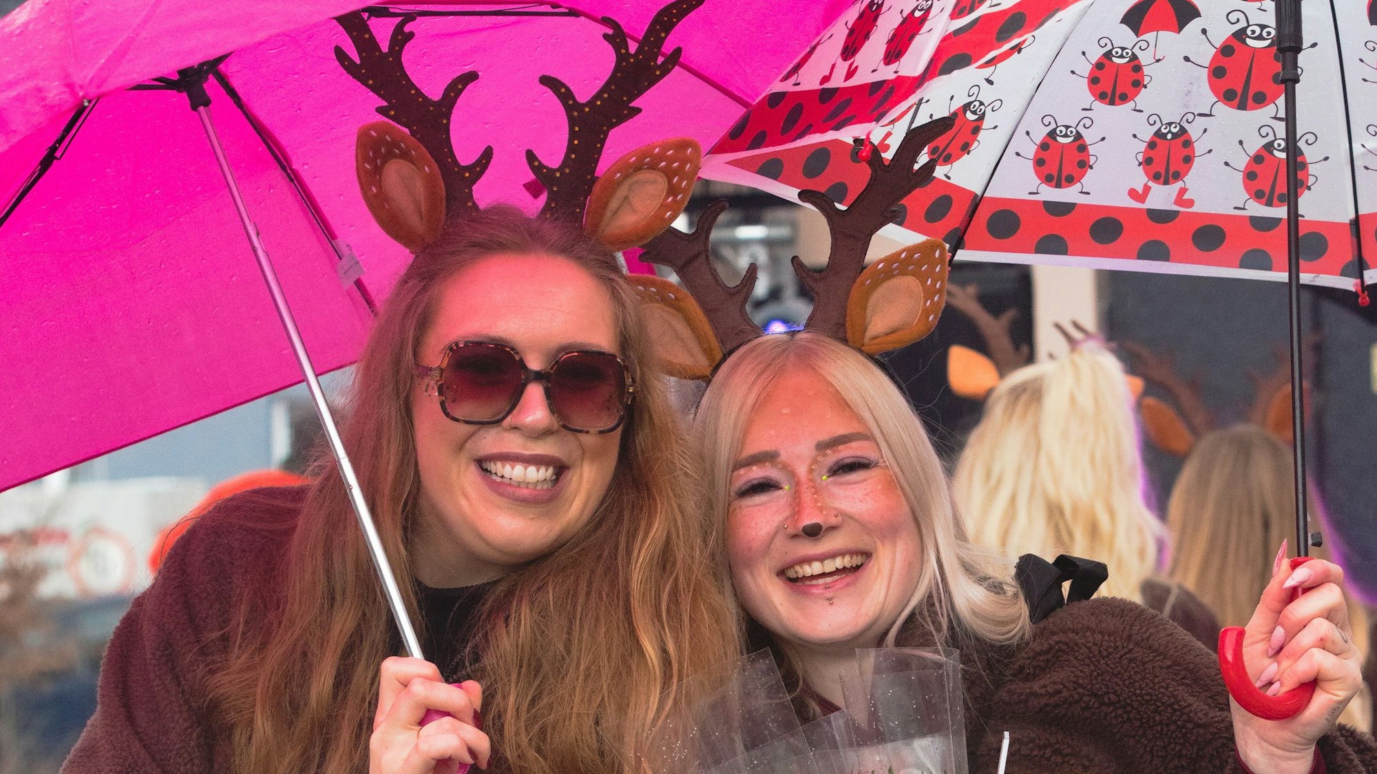 Zwei kostümierte Frauen halten Regenschirme über sich.