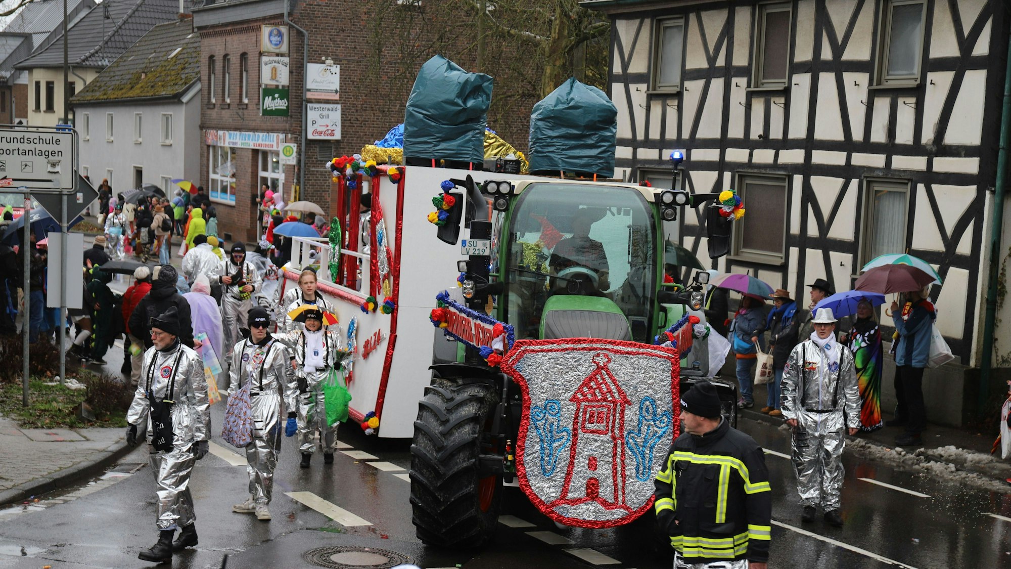Der Festwagen der Freiwilligen Feuerwehr nimmt die Kurve auf die L 268 Richtung Süchterscheid, die Wagenengel in Silber.