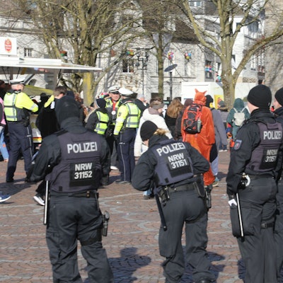 Mitglieder einer Einsatzhundertschaft der Polizei stehen am Karnevalszug Bergisch Gladbach auf dem Konrad-Adenauer-Platz.