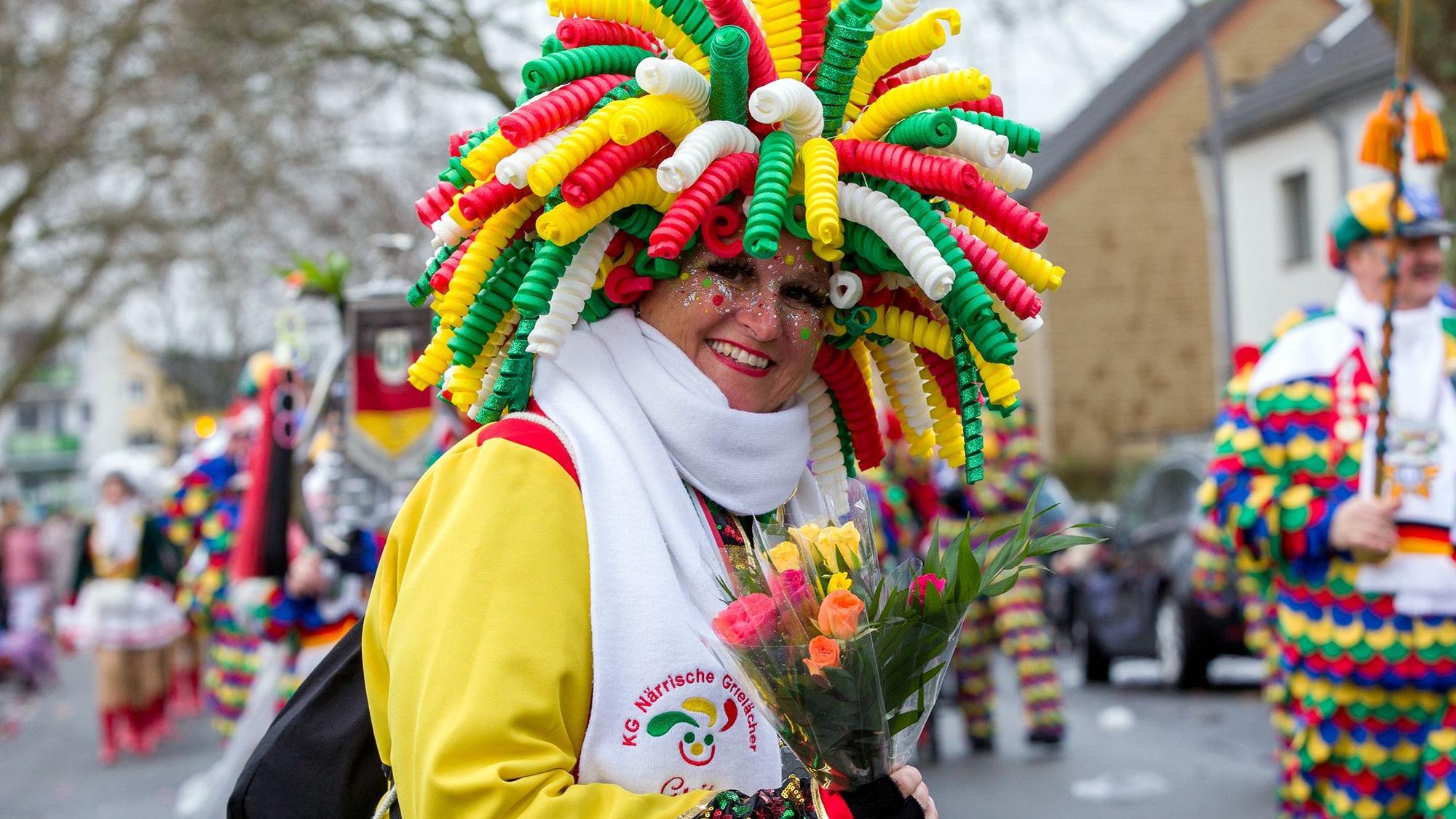Eine Frau mit irrem Kopfschmuck verteilt Strüßjer.