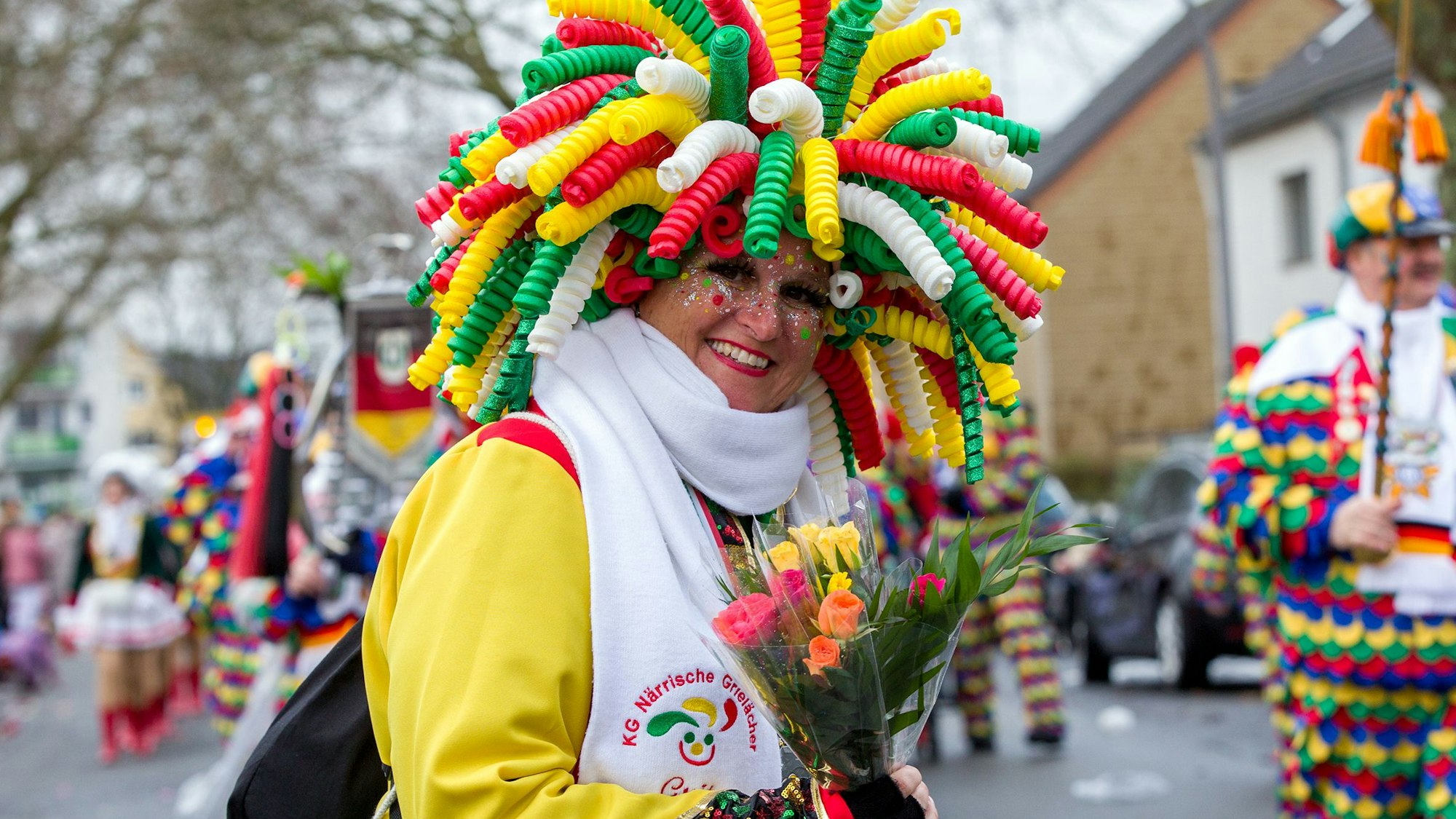 Eine Frau mit irrem Kopfschmuck verteilt Strüßjer.