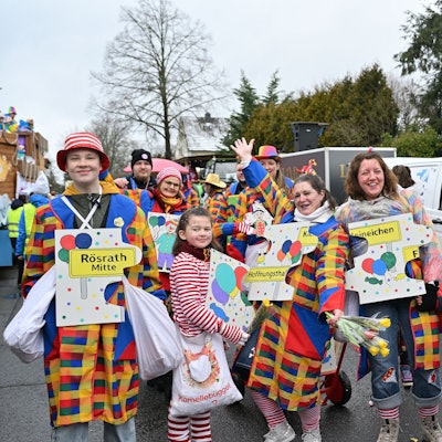 Eine Gruppe bunt gekleideter Leute mit großen Puzzleteilen aus Pappe vor der Brust, auf denen die Namen der Rösrather Stadtteile stehen.