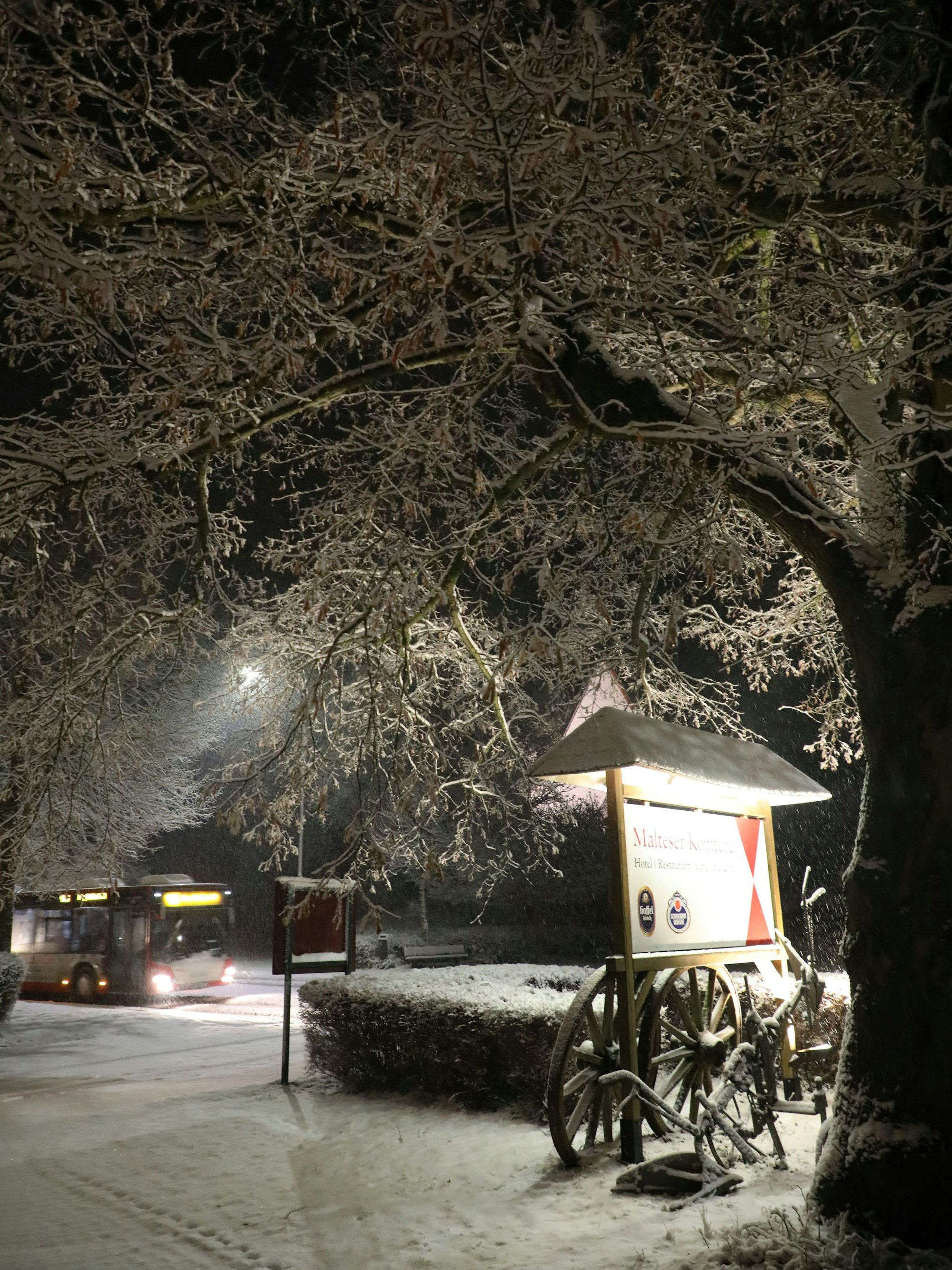 Ein Bus fährt an der winterlich verschneiten Außenwerbung der Malteser Komturei Herrenstrunden vorbei.