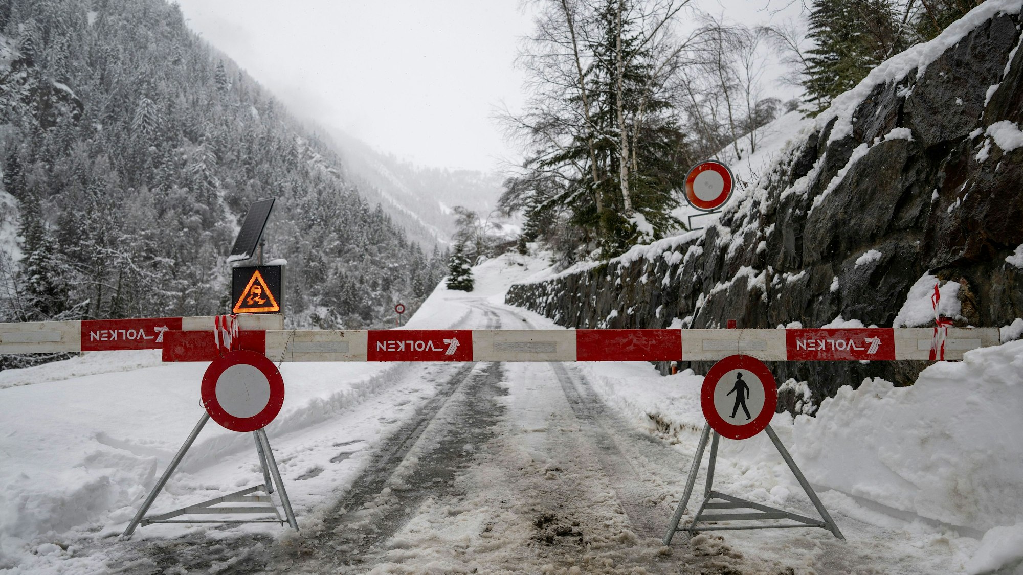 16.02.2026, Schweiz, Goppenstein: Blick auf eine gesperrte Straße zur Stockgalerie, bei der zwischen Goppenstein und Hohtenn ein Personenzug des Bahnunternehmens BLS entgleist ist und 30 Personen evakuiert wurden. Die Bahnstrecke zwischen Goppenstein und Brig ist unterbrochen. Foto: Peter Schneider/KEYSTONE/dpa +++ dpa-Bildfunk +++