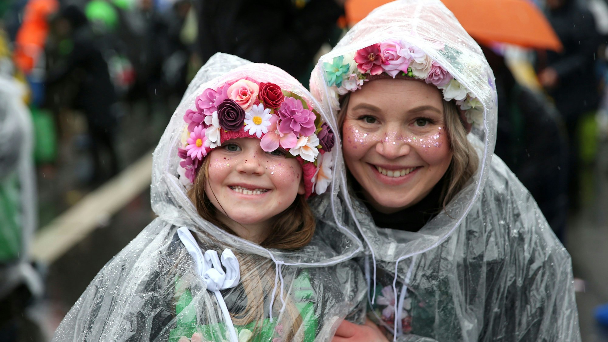 Eine Mutter mit ihrer Tochter im Regencape bei einem Karnevalszug.