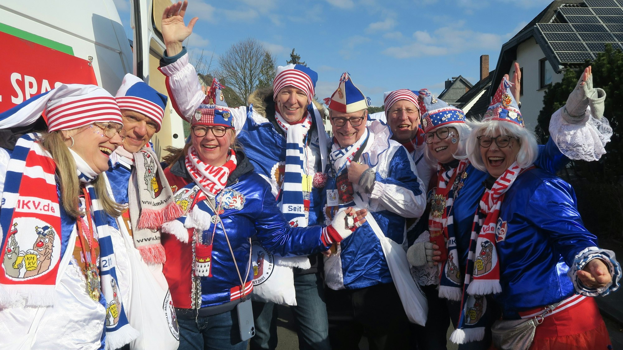 Eine Gruppe blau-weiß gekleideter Jecken mit rot-weißen Schals steht am Zugweg in Brück.