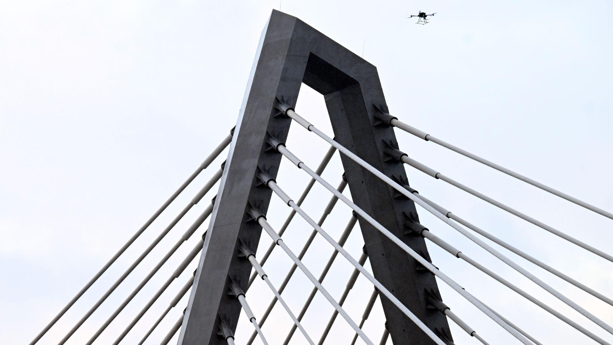 16.02.2026, Nordrhein-Westfalen, Leverkusen: Eine Drohne steigt neben den Drahtseilen der Leverkusener Rheinbrücke auf, um den Zustand der Konstruktion zu überprüfen. Die Autobahnmeisterei sperrte die Autobahn 1 (A1) in beide Richtungen, nachdem sich über Nacht Eis gebildet hatte, das auf darunter fahrende Fahrzeuge hätte stürzen können. Foto: Roberto Pfeil/dpa +++ dpa-Bildfunk +++