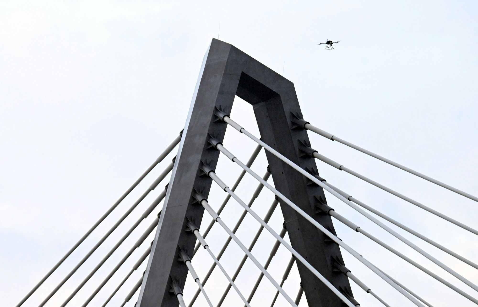 16.02.2026, Nordrhein-Westfalen, Leverkusen: Eine Drohne steigt neben den Drahtseilen der Leverkusener Rheinbrücke auf, um den Zustand der Konstruktion zu überprüfen. Die Autobahnmeisterei sperrte die Autobahn 1 (A1) in beide Richtungen, nachdem sich über Nacht Eis gebildet hatte, das auf darunter fahrende Fahrzeuge hätte stürzen können. Foto: Roberto Pfeil/dpa +++ dpa-Bildfunk +++