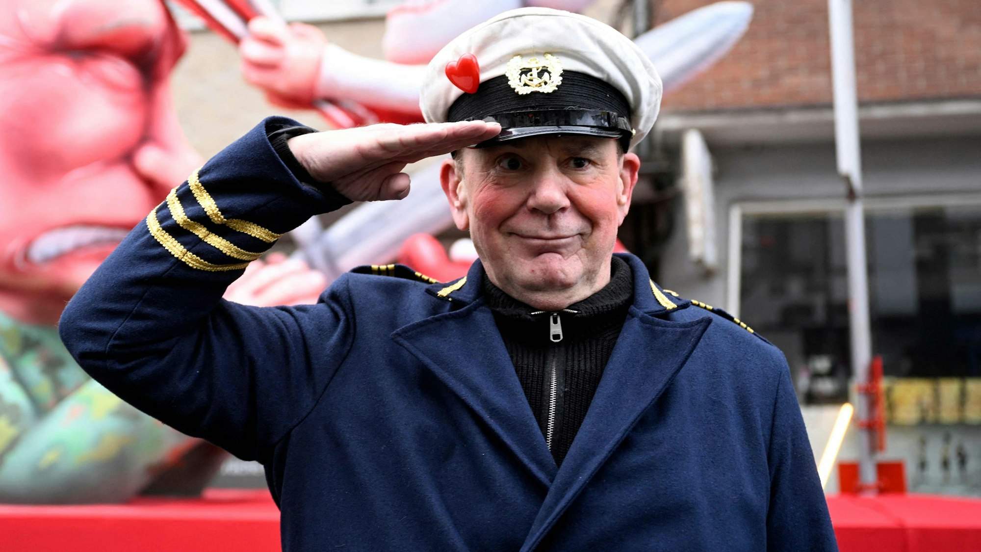 Jacques Tilly, Wagenbauer, steht vor dem Mottowagen auf dem Putin die Düsseldorfer Karnevalsfigur Hoppeditz aufspießt.