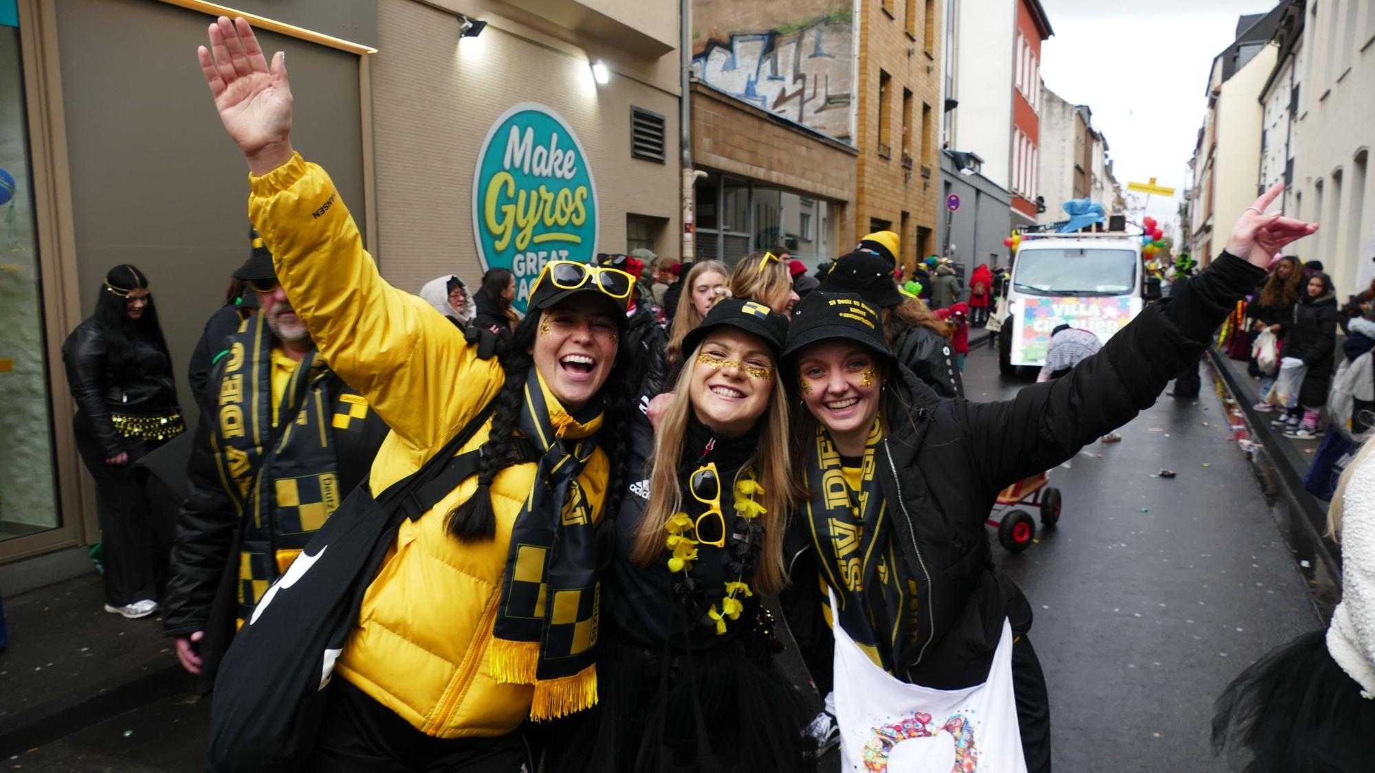 Drei Frauen in Schwarz-Gold stehen zusammen auf dem Zugweg.